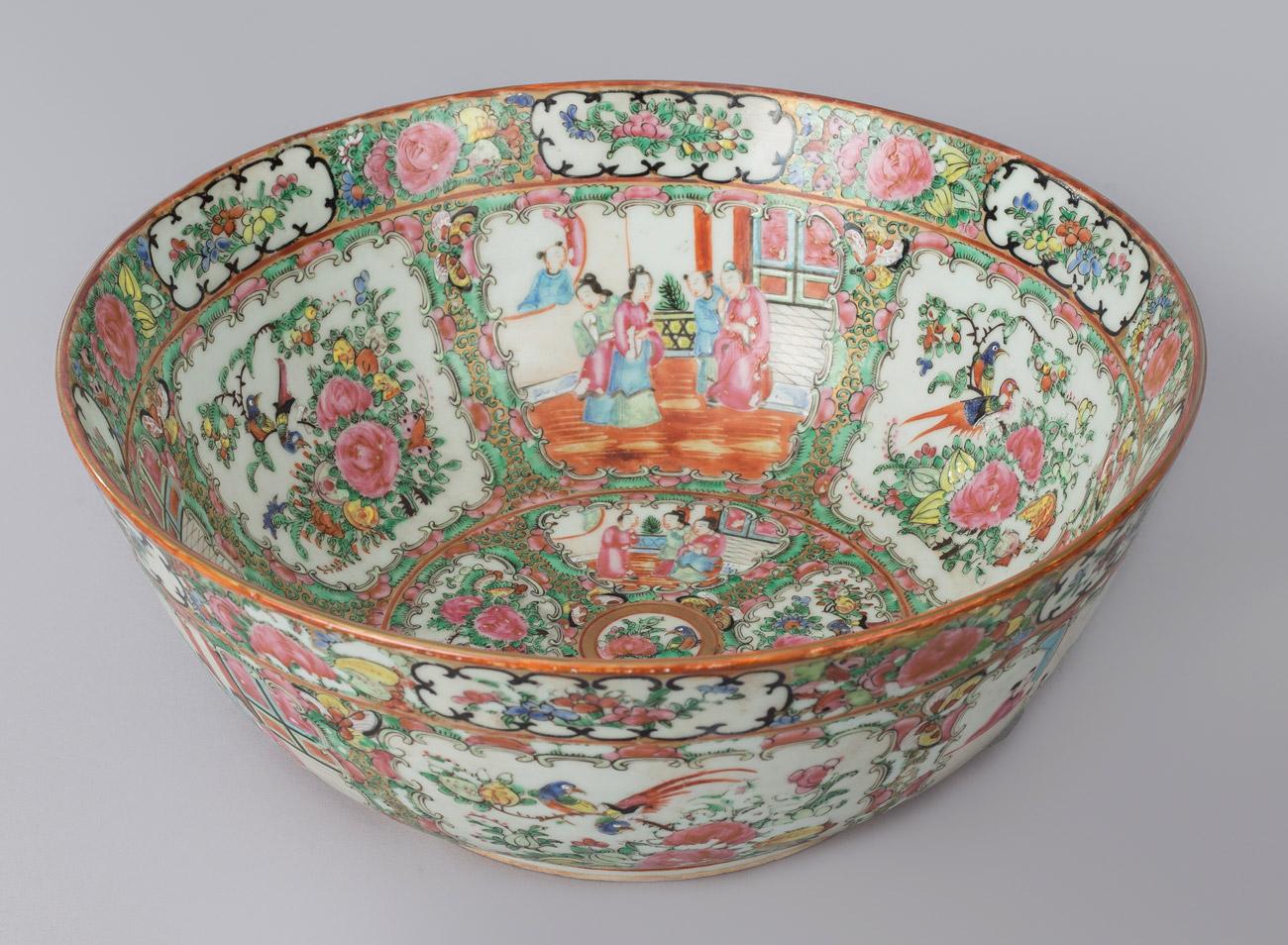 Chinese export Rose Medallion porcelain and enameled punch bowl in the famille rose palette decorated with exterior and interior alternating panels of courtly ladies in palace scenes and garden flowers and parrots, framed by bands of foliage and