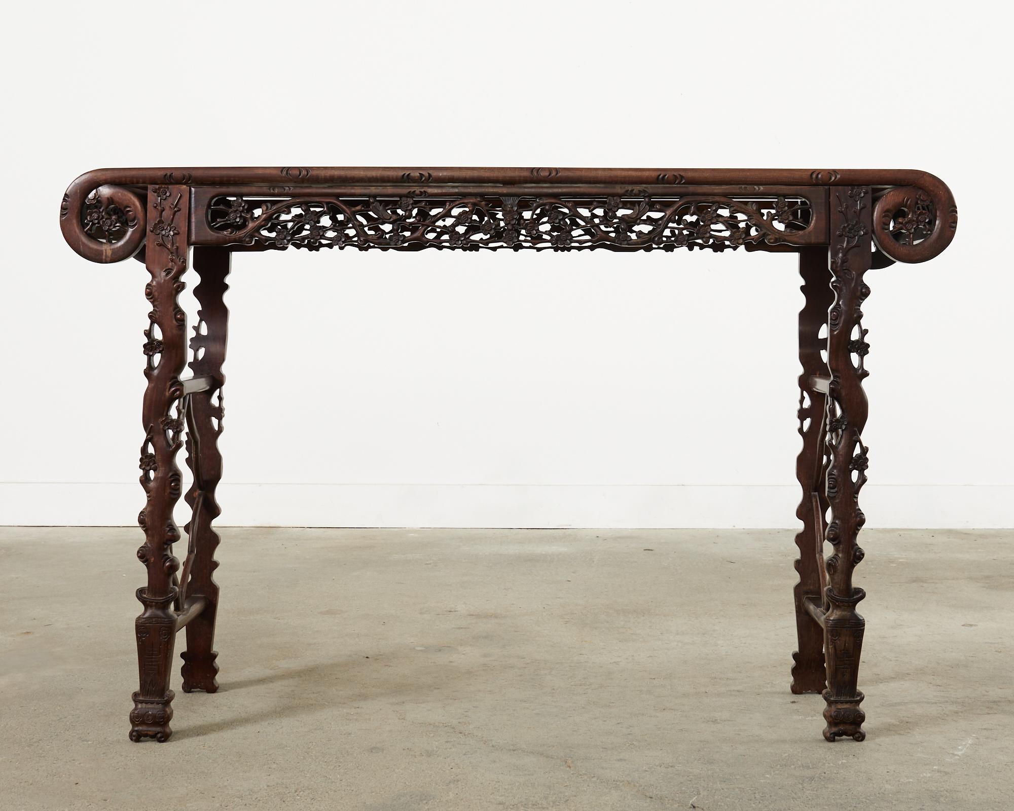 Exceptional Chinese Huali rosewood table with remarkably straight wood grain patterns and distinctive carving. The aprons are carved in an intricate lattice work of blossoms and birds. The legs feature delicate faux bois and prunus blossoms. From