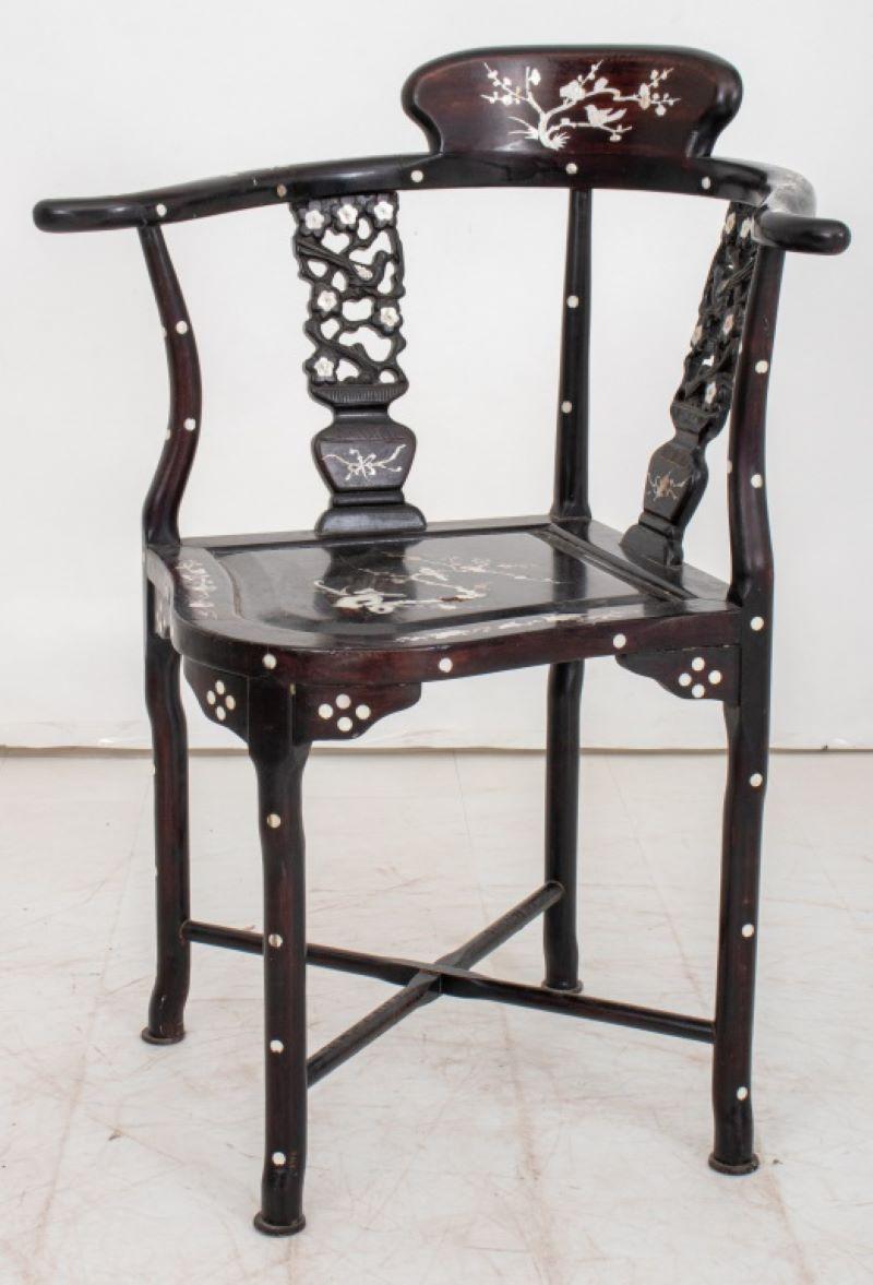 Chinese Export Mother-of-Pearl Inlaid Ebonized Corner Chair, the sweeping horseshoe-shaped crestrail centered by a prunus-inlaid rest, and supported by two reticulated and inlaid splats in the forms of potted prunus, on a shaped square seat
