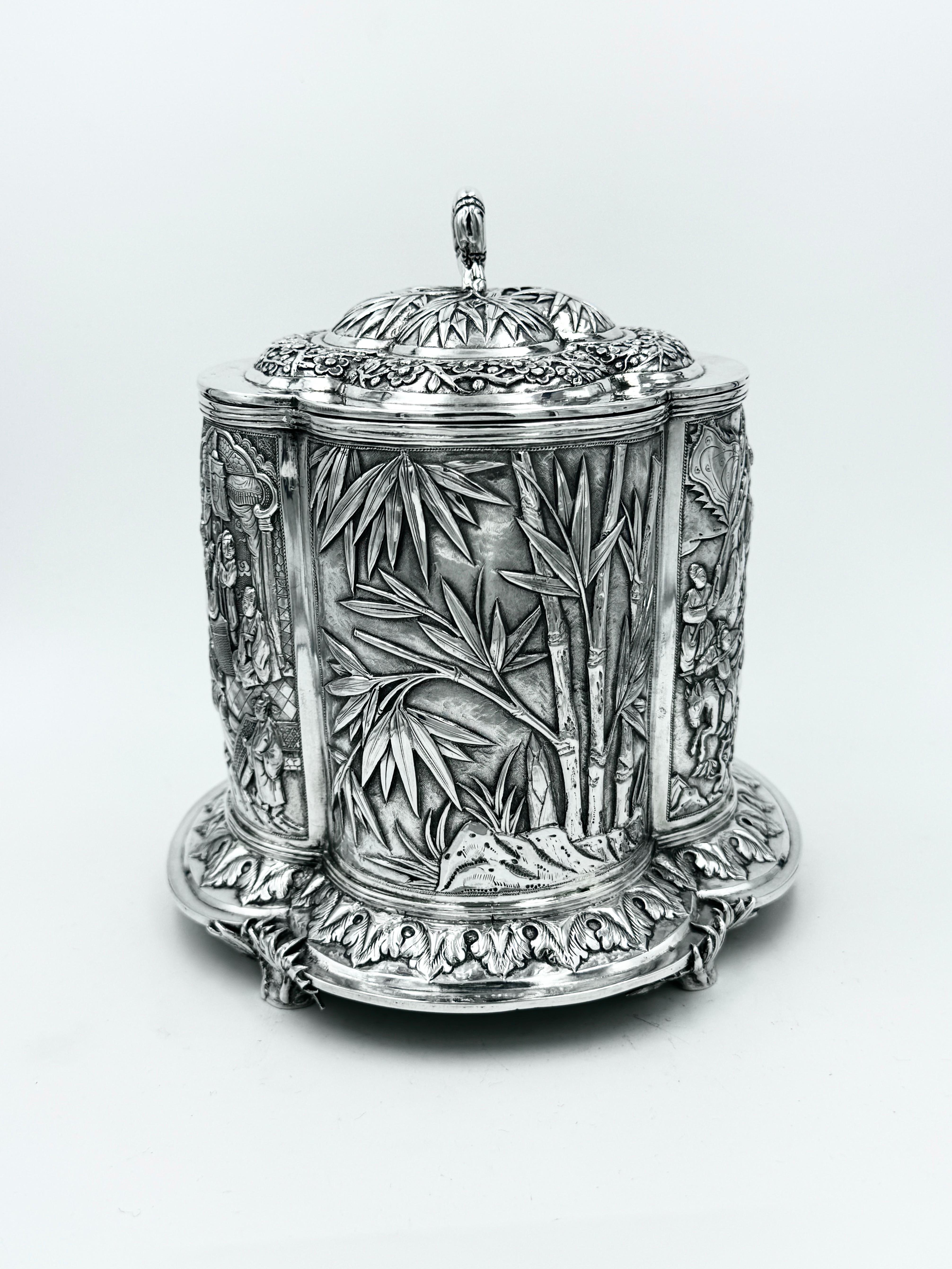 Caja para galletas de plata de exportación china, circa 1890, de forma cuatrifoliar. Los paneles frontal y posterior están repujados y cincelados con escenas de la corte y batallas, y los dos paneles laterales con bambú. La tapa extraíble tiene un