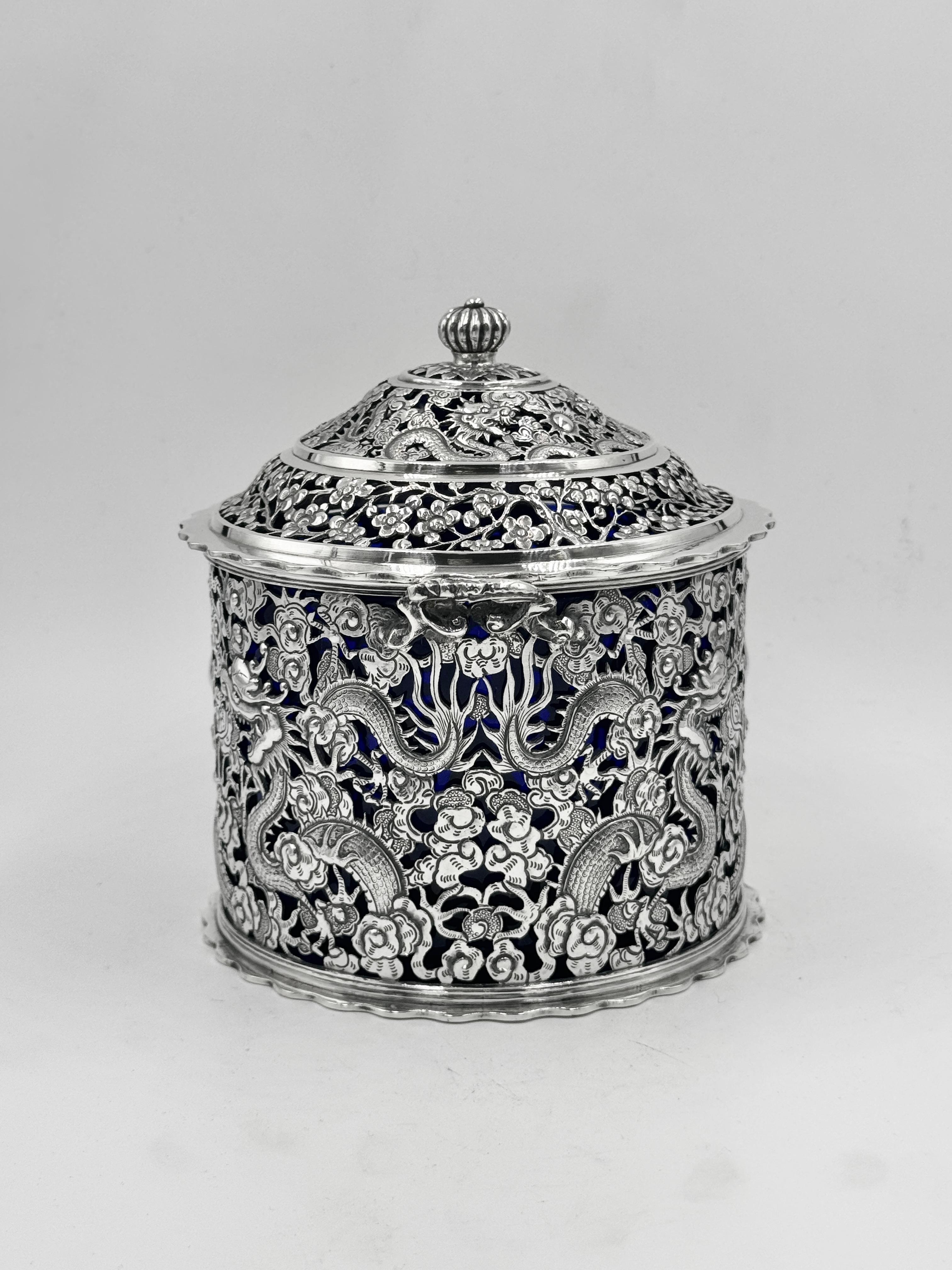 Caja de galletas de plata de exportación china, hacia 1895, con marcas de importación británicas de Glasgow 1902, y un forro posterior de cristal azul.
La caja está perforada con dos pares de dragones opuestos, y la tapa está perforada con tres