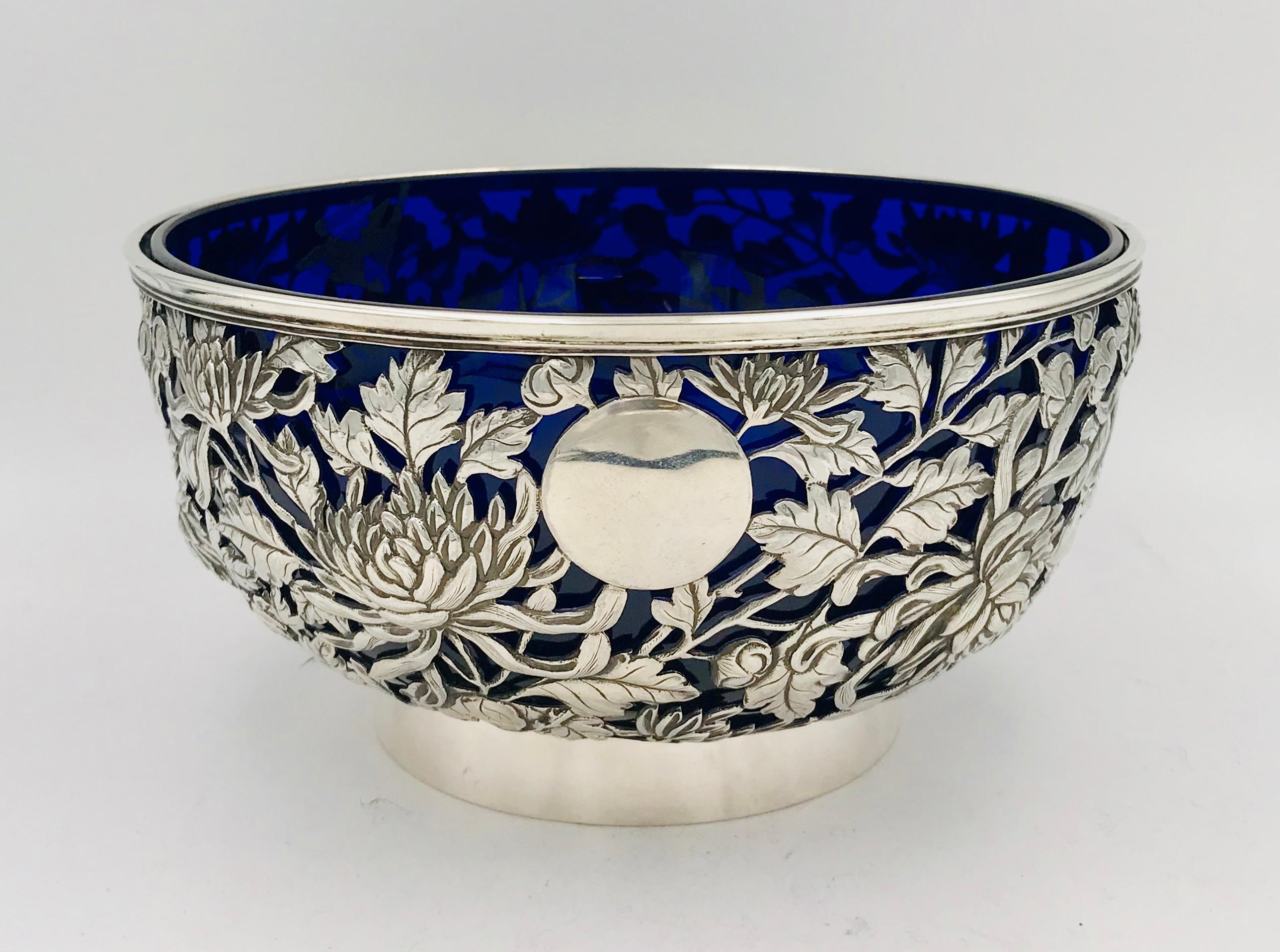 A Chinese export silver bowl with blue glass liner.
The bowl is pierced and has wonderfully detailed chrysanthemum decoration.
The bowl has a vacant cartouche and sits on a plain collet foot.
The bowl was retailed by Chong Woo in Hong Kong