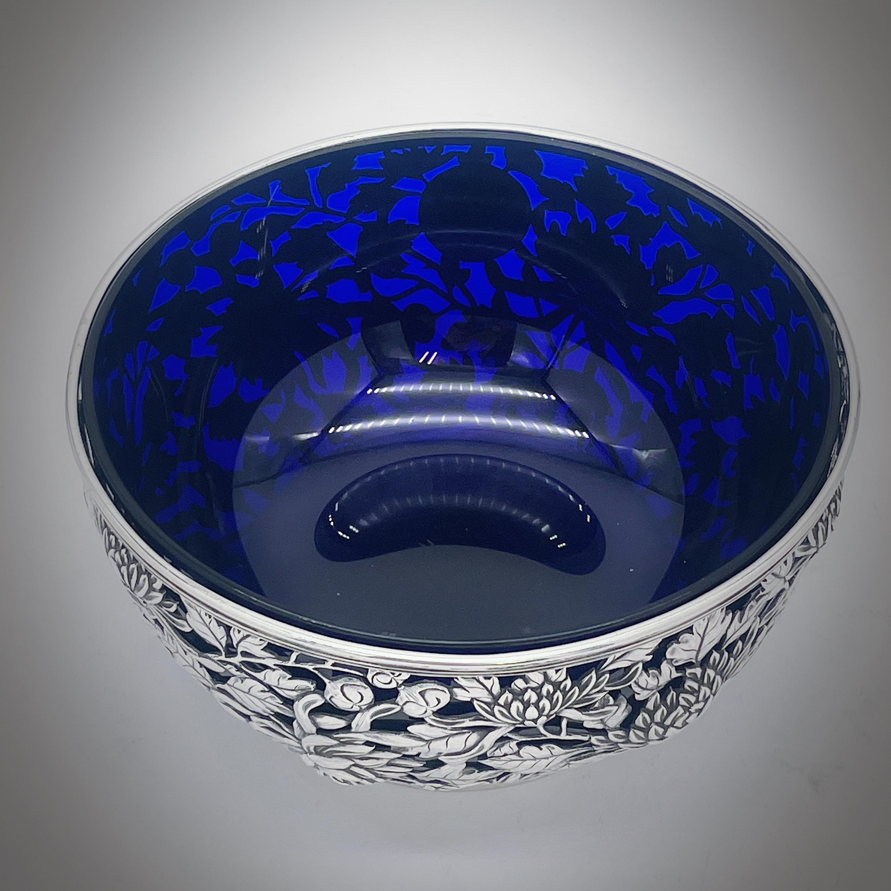 Un bol en argent d'exportation chinois vers 1890, avec une doublure en verre bleu plus tardive. La coupe est percée d'un décor de chrysanthèmes merveilleusement détaillé, comporte un cartouche rond vacant et repose sur un pied à collet uni. Le bol a