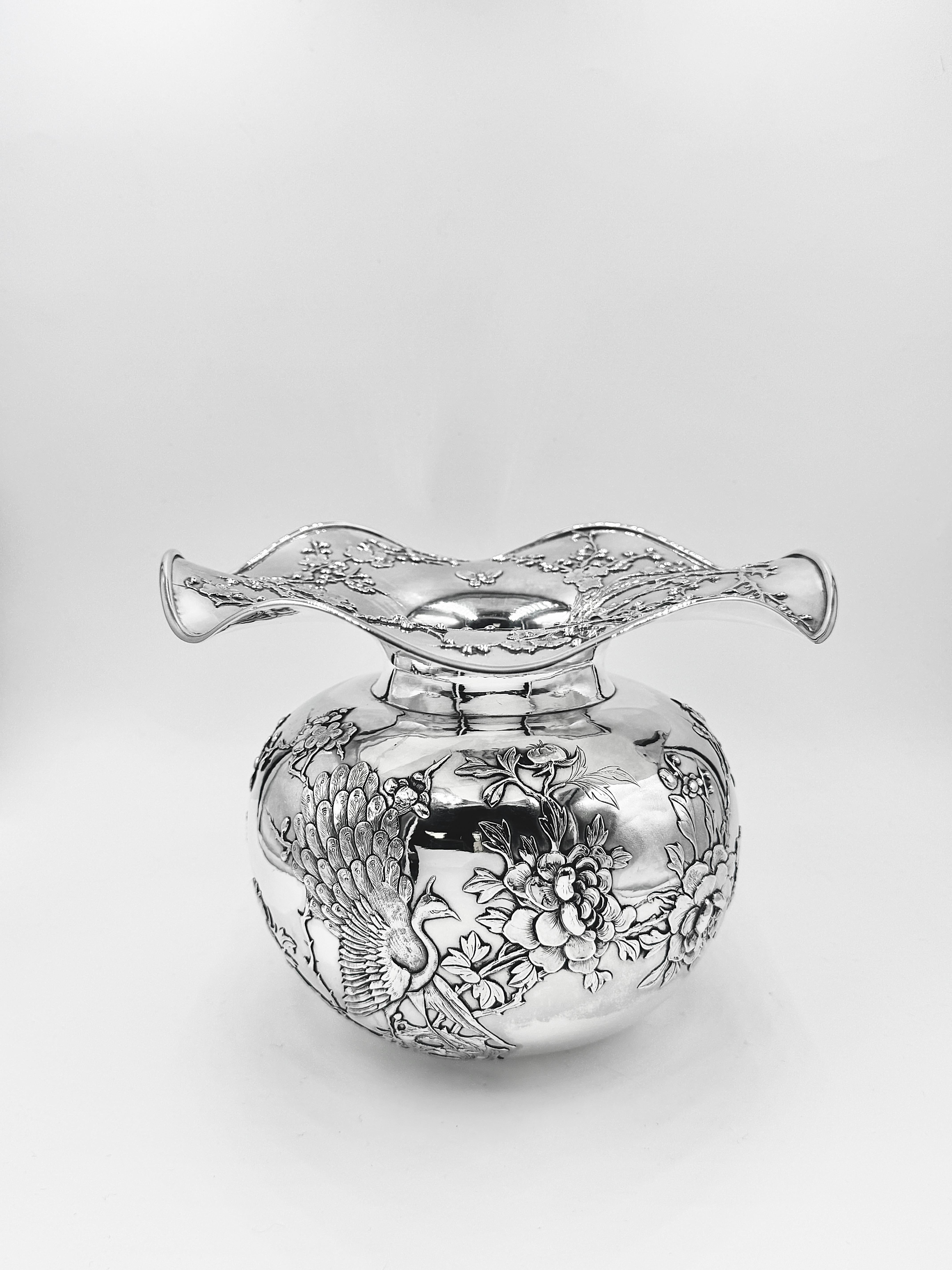 Chinesische Export-Silberschale, um 1895, mit aufgelegtem Dekor aus zwei Pfauen auf jeder Seite des kugelförmigen Körpers und vier Schmetterlingen, die zwischen Pfingstrosen und Pflaumenblüten fliegen. Die Schale hat einen breiten, gewellten Rand