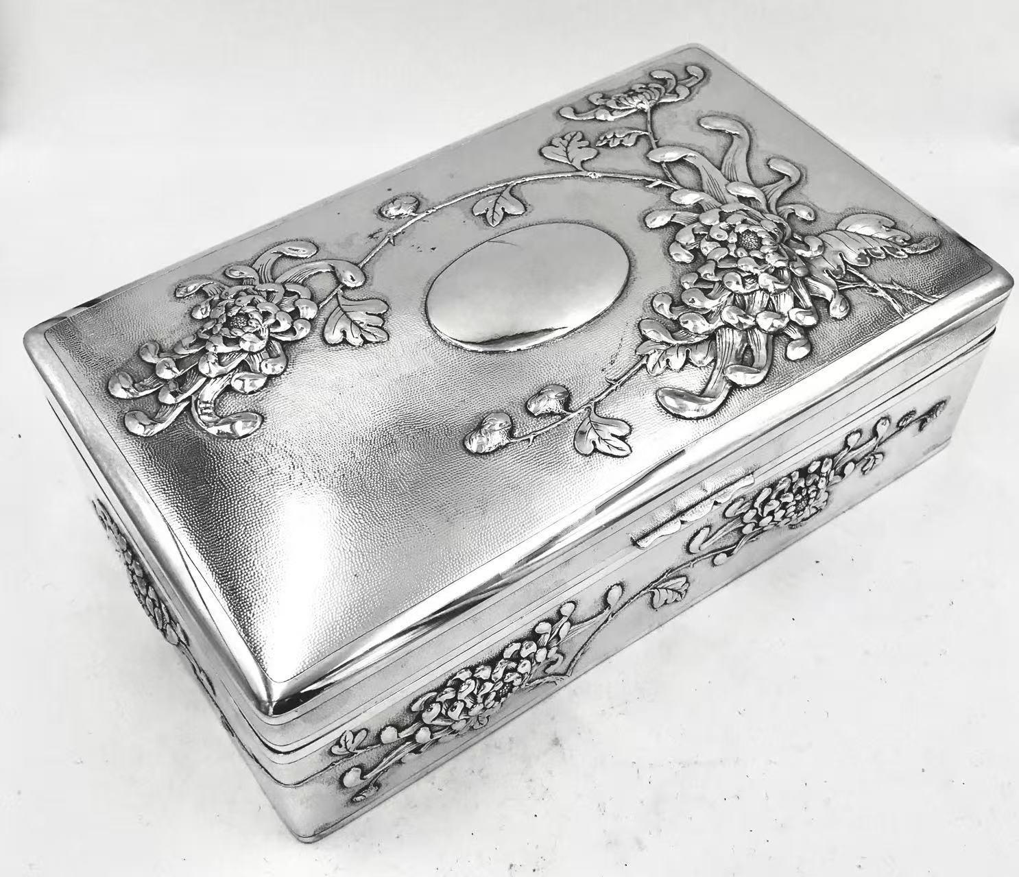 Esta gran caja china de plata está cincelada con flores de crisantemo sobre un fondo de grano fino. Marcado Hung Chong para el minorista, y con una marca de fabricante de 