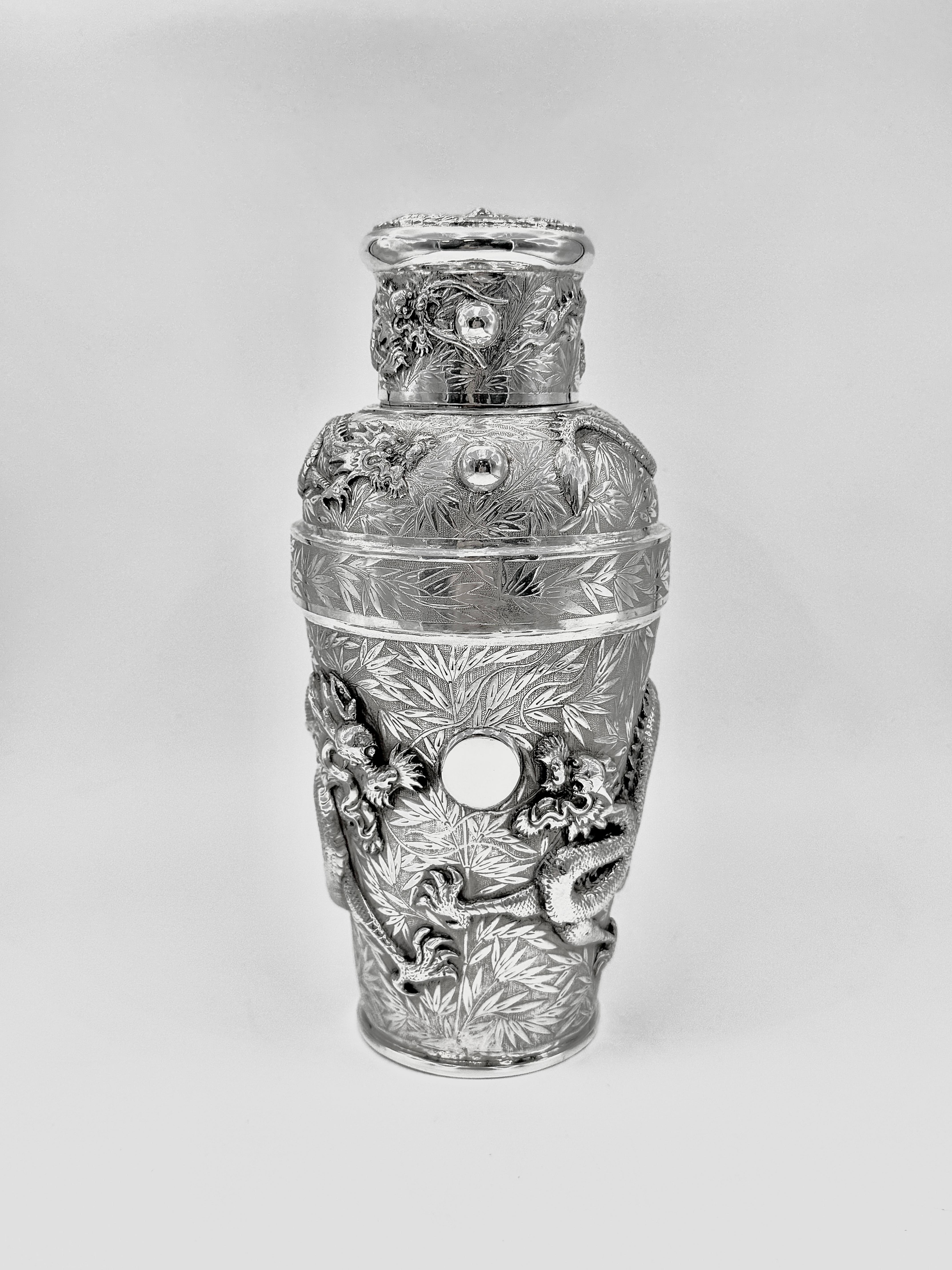 Coctelera china de plata de exportación, fabricada por Tu Mao Xing (涂茂興) en Jiujiang (九江), hacia 1930. Finamente repujado y cincelado en altorrelieve con dos dragones opuestos que persiguen una perla en el cuerpo, otro dragón enroscado alrededor de