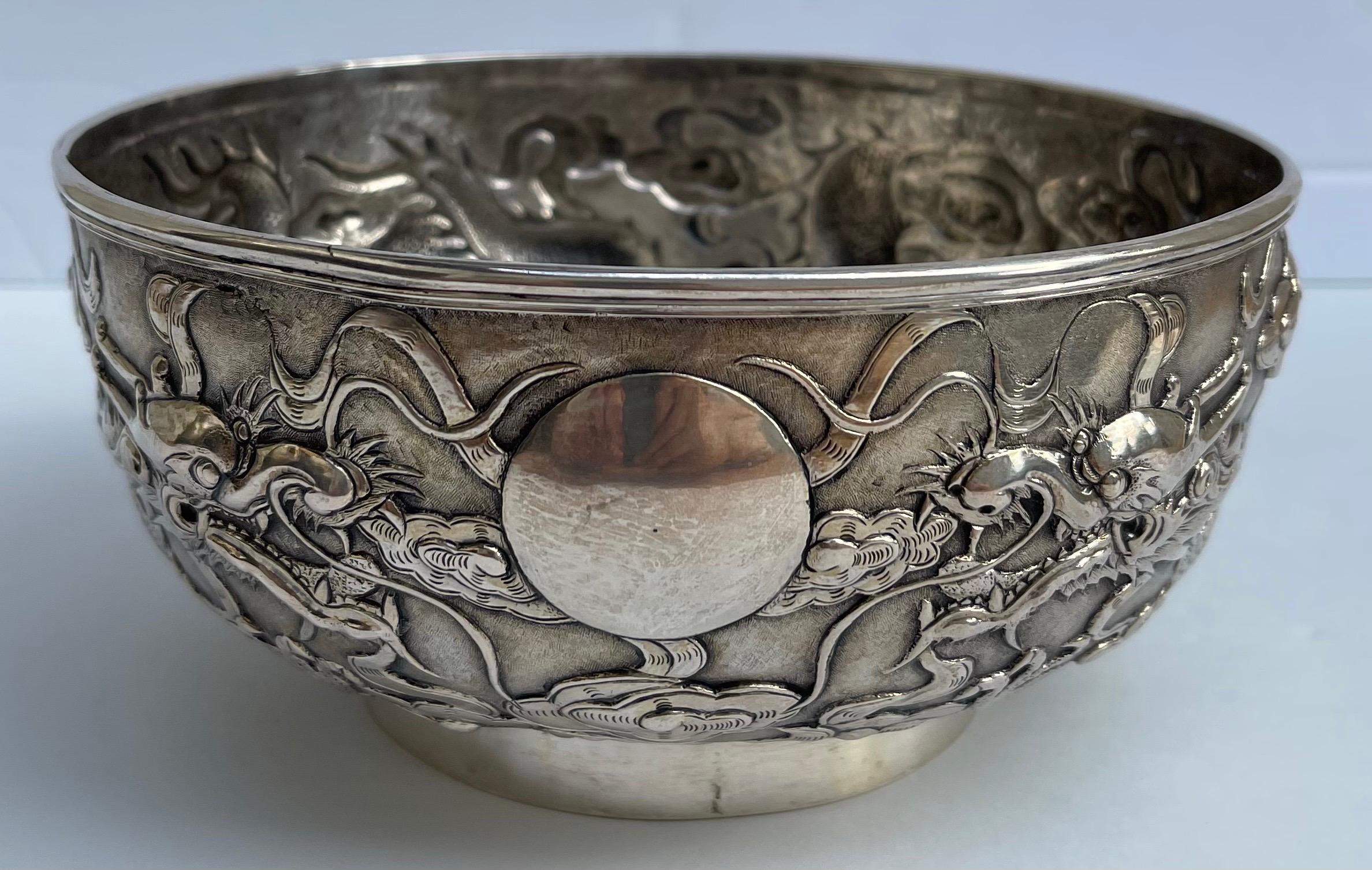 Coupe en argent d'exportation chinoise du 19e siècle. Décorée d'un audacieux motif de dragon en repoussé, deux dragons se disputant une perle de sagesse flamboyante au centre, parmi des nuages et un fond ciselé. Marqué sur la face inférieure