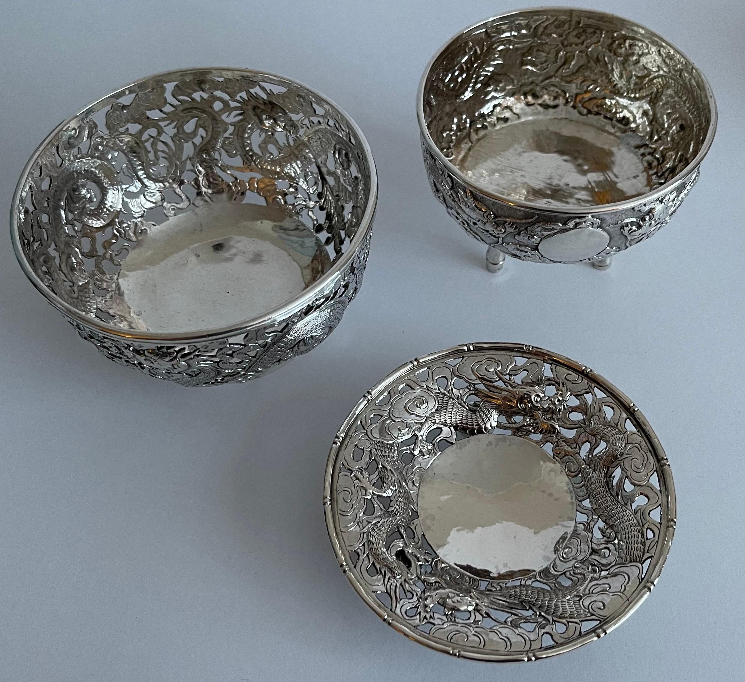 Set of three Chinese export silver bowls.

Tripod bowl has stylized bamboo legs and center medallion (no monogram). Featuring two repoussè dragons. Tripod bowl is marked LC (Lee Ching) on underside and measure 3” tall x 4” diameter. 

Small