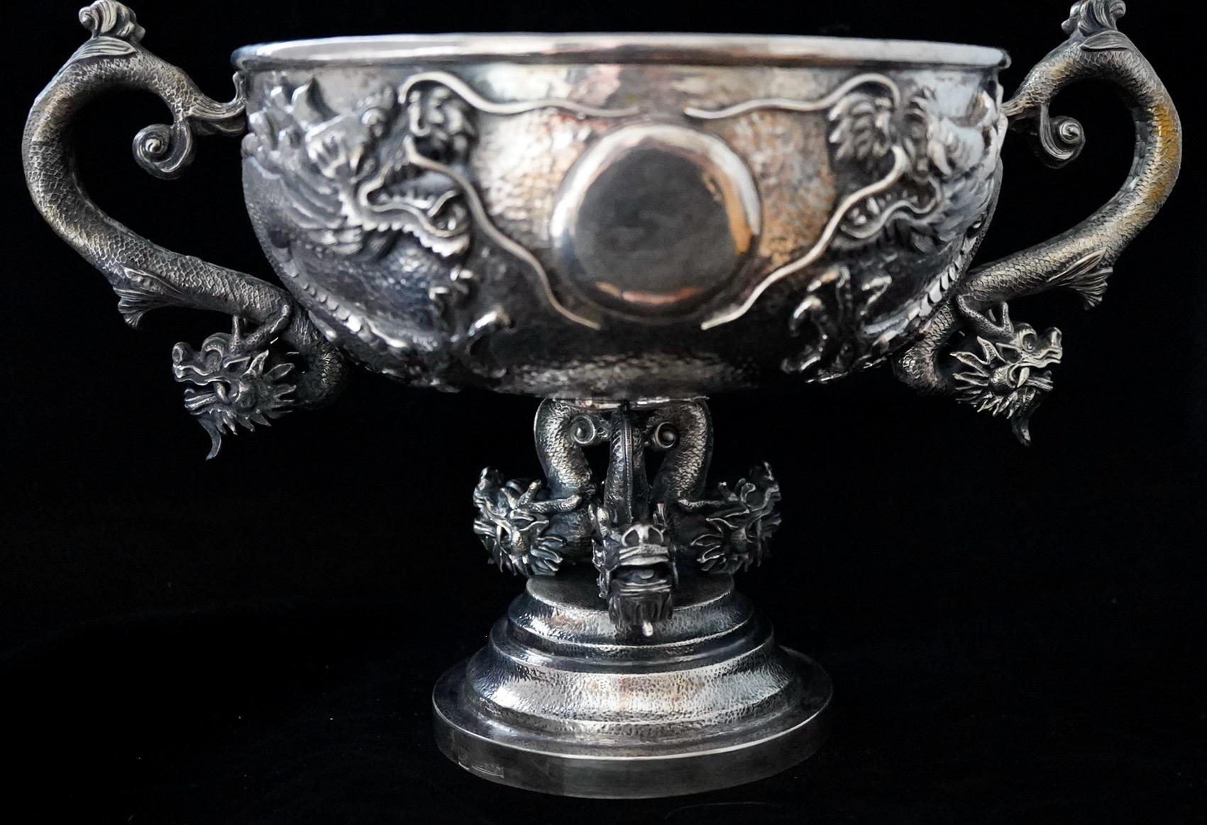 Chinese Export Silver Centerpiece with dragon decoration. The centerpiece bowl has two repousse dragons with attached dragon handles. The bowl rests on three cast dragons. The centerpiece is 12.5 inches handle to handle, 7.75 inches tall, and