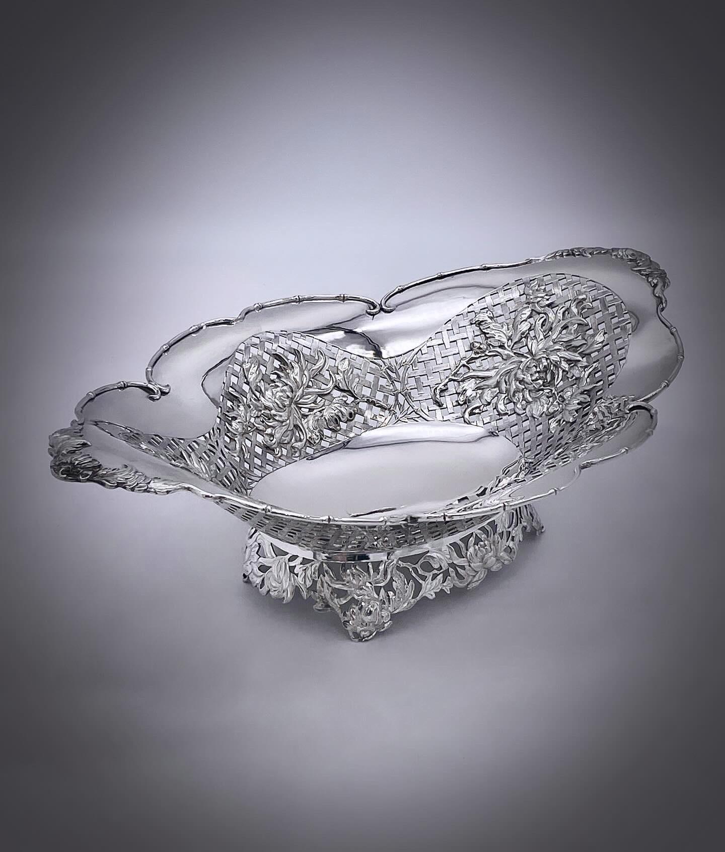 A Chinese export silver fruit dish of shaped oval form. The dish has applied chrysanthemum on engraved basket weave piercing, and the base is a skirt of pierced chrysanthemum. Made by Jing Xiang 敬祥 for the Shanghai firm of Luen Wo, circa 1900.
