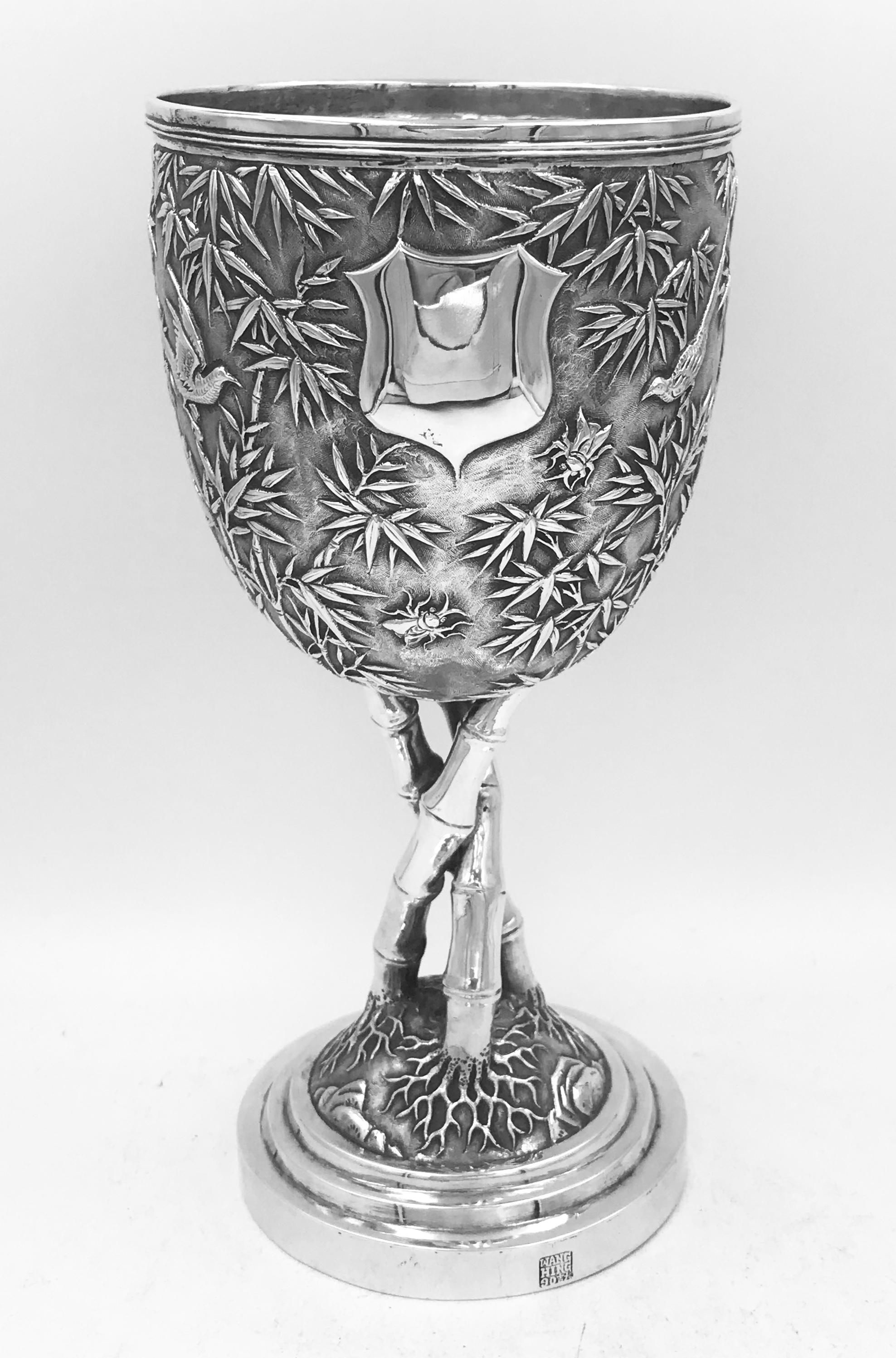 A Chinese export silver goblet circa 1890, decorated with birds, bugs and bamboo on a matte background. The stem is formed of 3 shoots of bamboo and there is a vacant shield-shape cartouche. Marked with the retailer's mark of Wang Hing '宏兴‘ and the