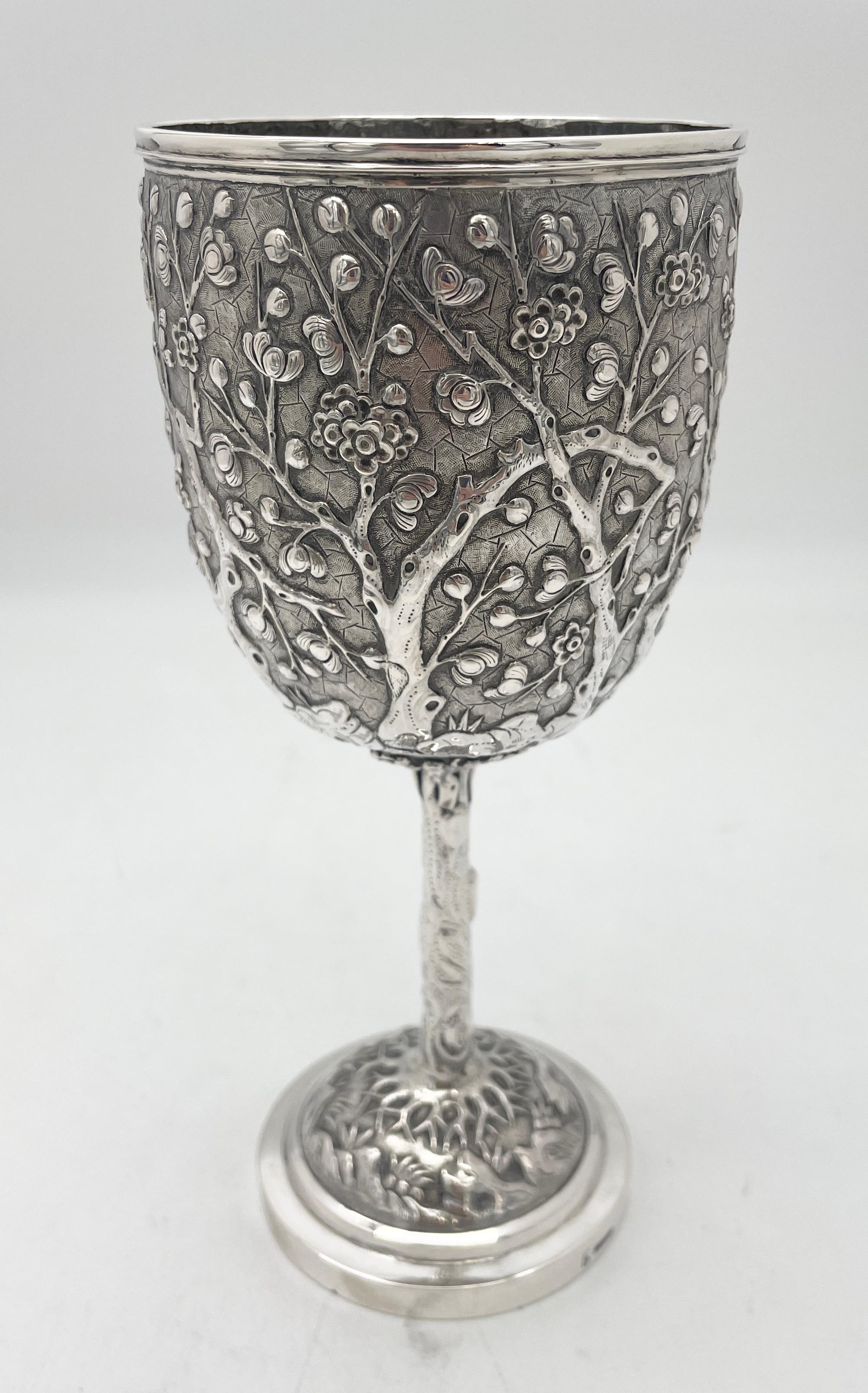 A Chinese export silver goblet with prunus decoration on a matte background, and the base and stem formed as prunus tree branch root. The body has a single round cartouche engraved 