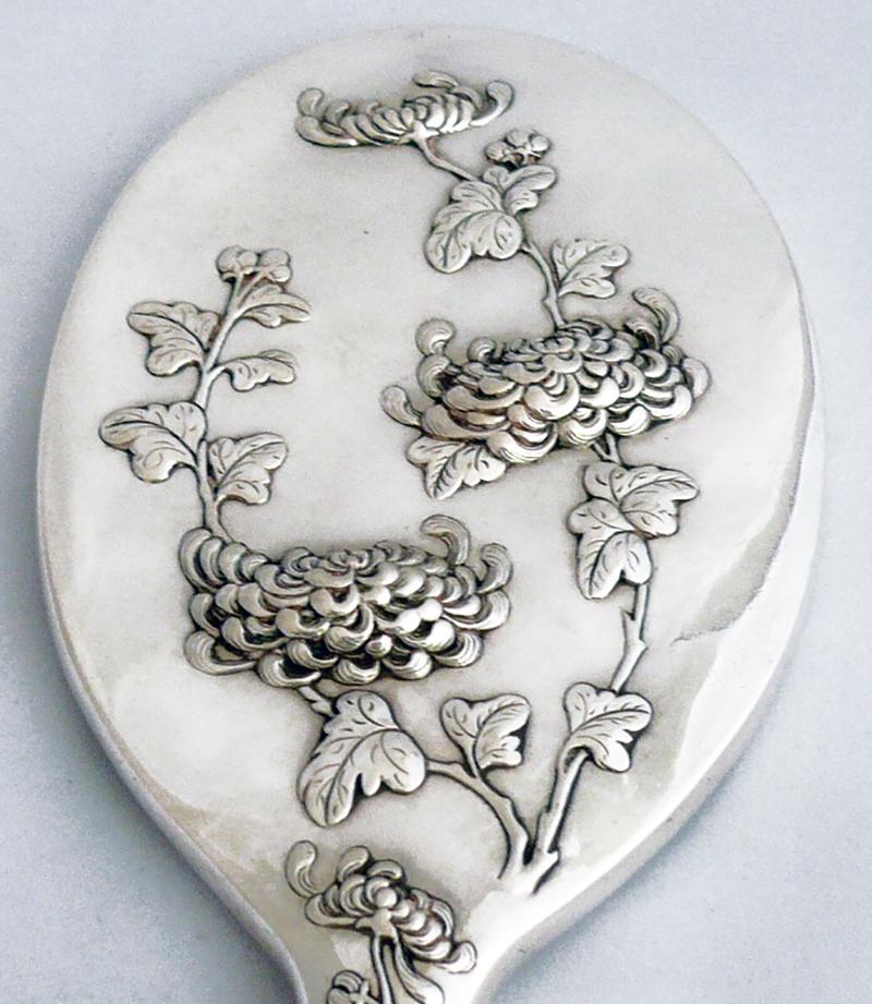 A large Chinese export silver hand mirror. The back of the mirror has been worked with trailing chrysanthemum flowers - that bloom through the Frost. 

An ideal gift for the mature lady

Fine condition.
