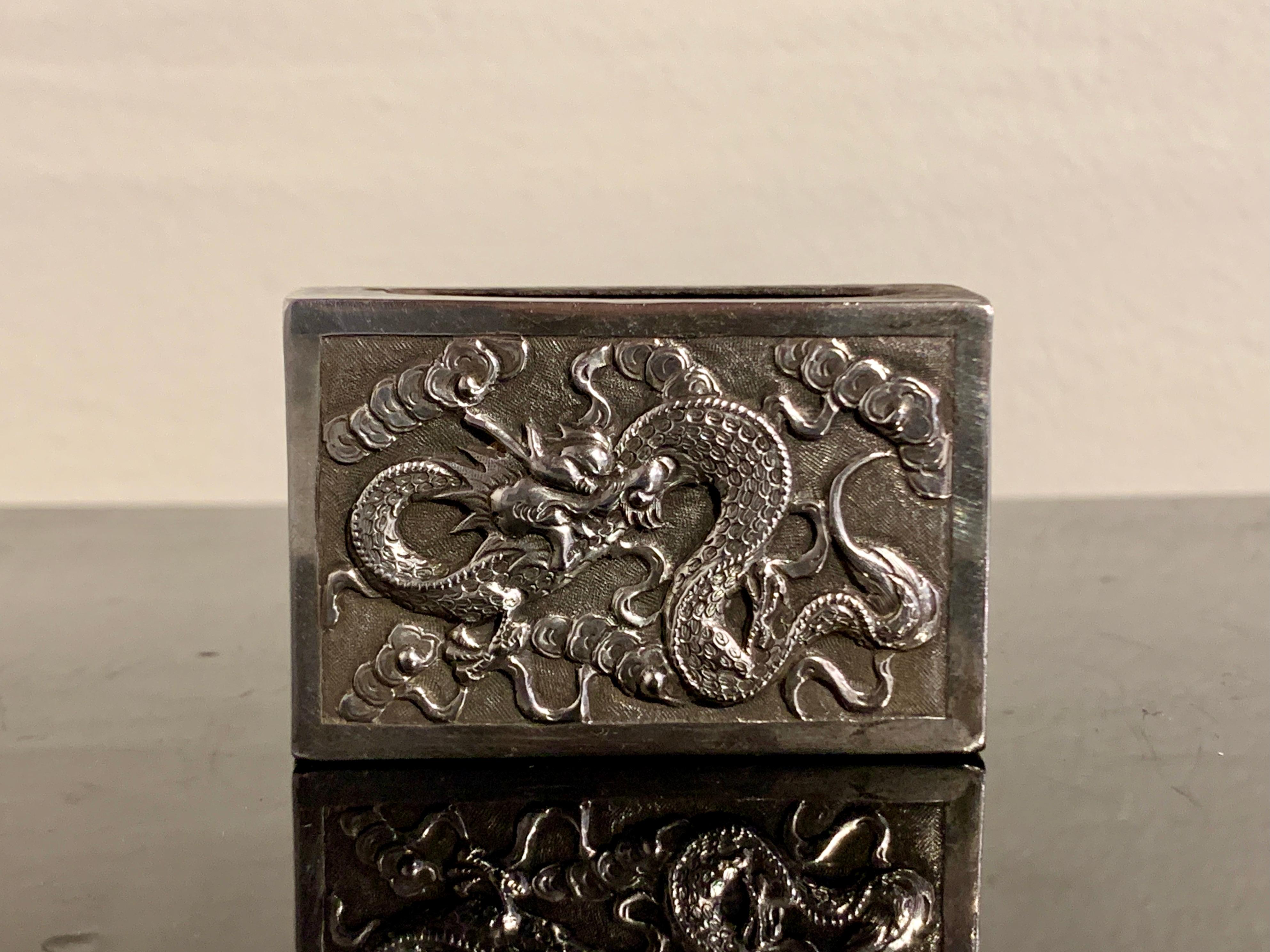 A wonderful Chinese export silver matchbox holder or cover, by Hone Wo, early 20th century, China.

The silver matchbox cover decorated with a fantastic dragon twisting and writhing in the clouds on one side - the shapes of the clouds reminiscent of