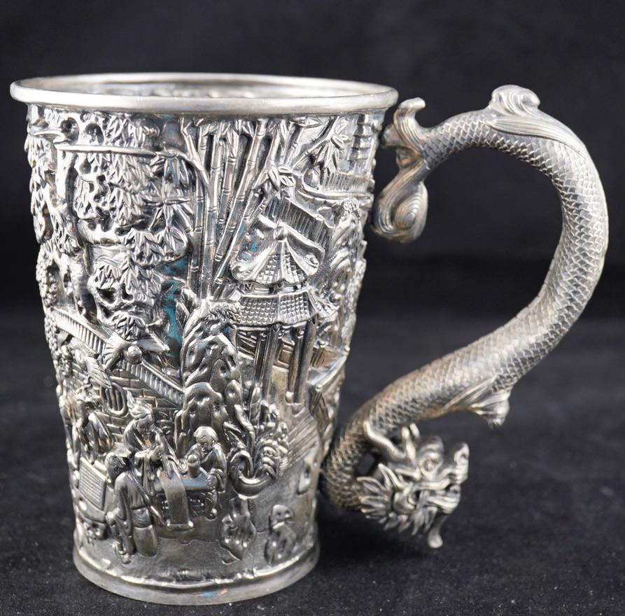 Chinese export heavy repousse dragon handle tankard. Decorated with landscapes and activities. Marked with CW fotr Cum Wo and Chinese character. Cum Wo workshop
known to operate in Hong Kong 1860-1920.
The tankard is 5 3/4