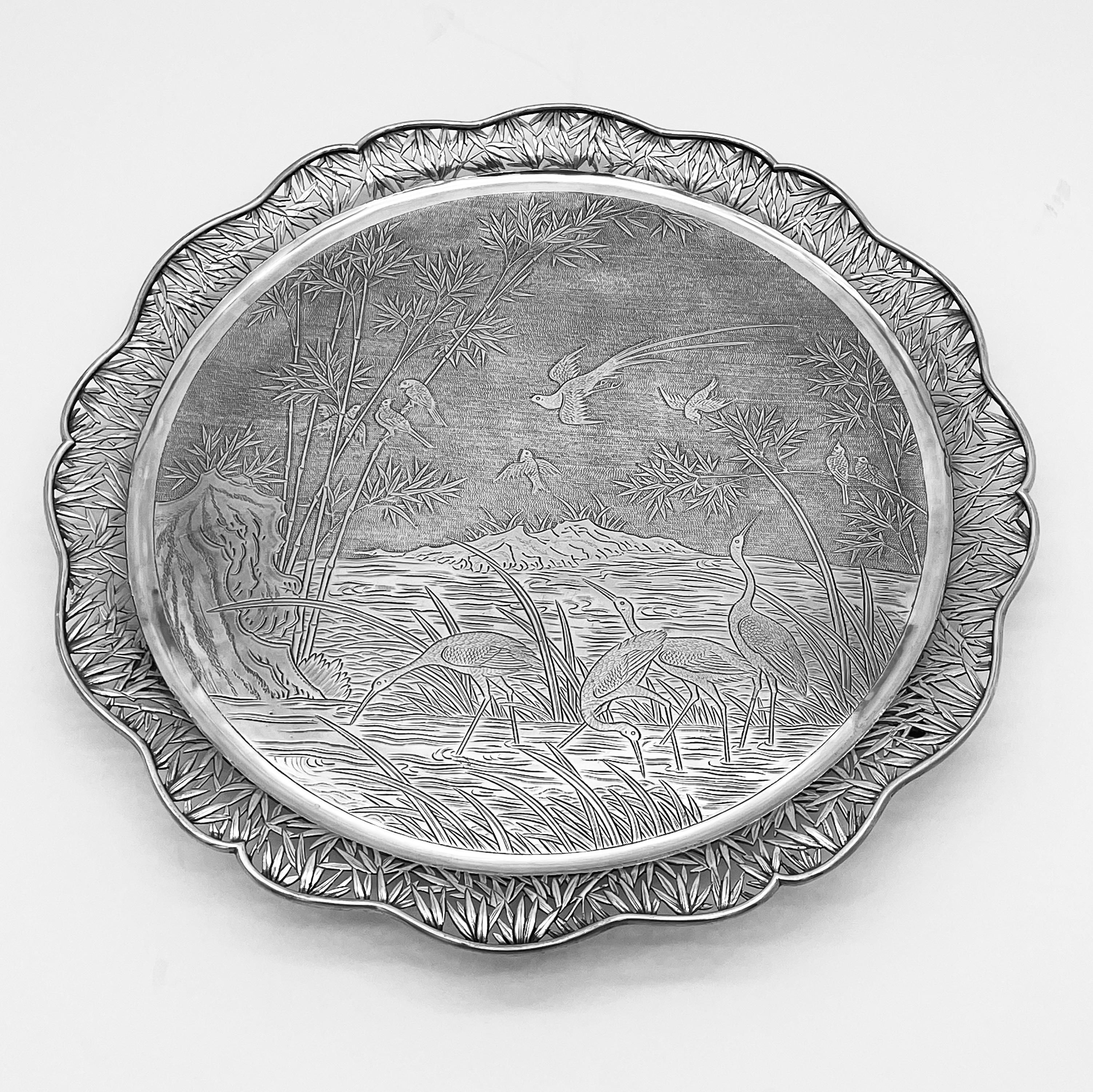 An exquisite Chinese Export Silver Salver embossed and chased with a captivating scene of graceful egrets wading in the pond, accompanied by the elegant flight of Chrysolophus (a type of pheasant) above, surrounded by bamboos and stones. The