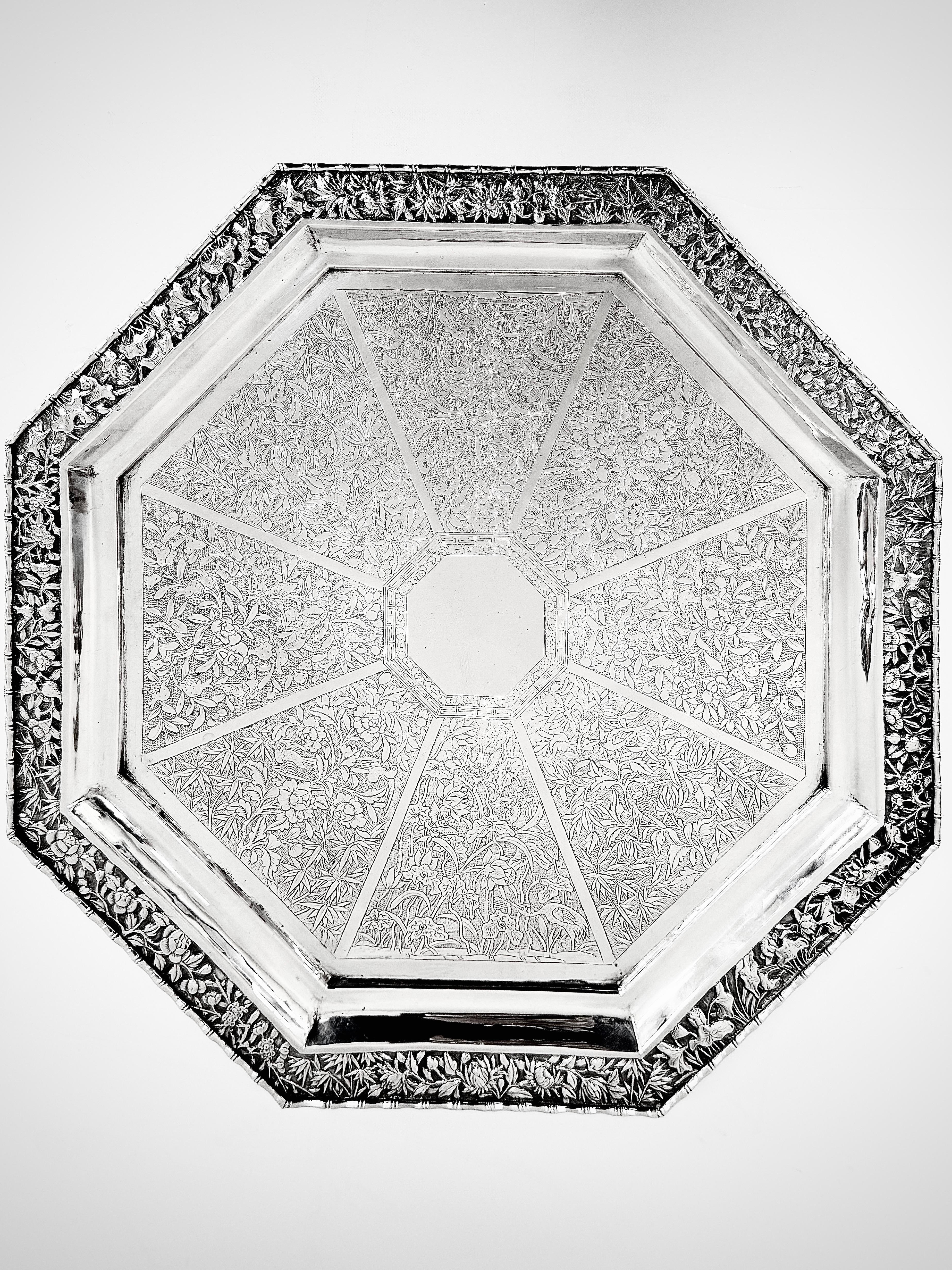 Bandeja de plata china de exportación, de forma octogonal, con ocho paneles que se abren en abanico desde el centro y están decorados con lotos y garcetas, urracas y peonías, mariposas y flores de granada, palomas y magnolias.  
Hay una marca de