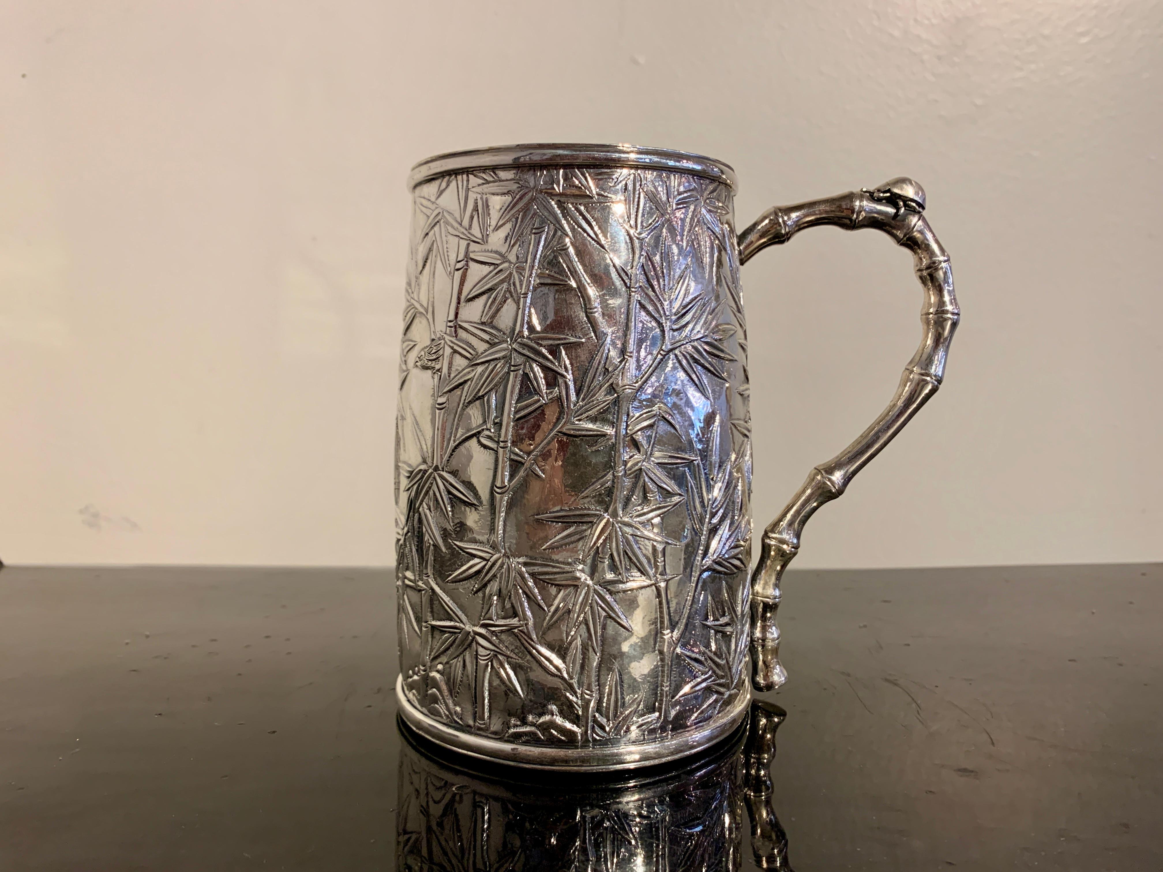 A wonderful Chinese export silver bamboo motif tankard by Luen Hing, circa 1920, Shanghai, China.

The large tankard with a slightly bulging and tapered body. The tankard decorated with a wonderfully organic design of leafy bamboo. Sparrows flit and