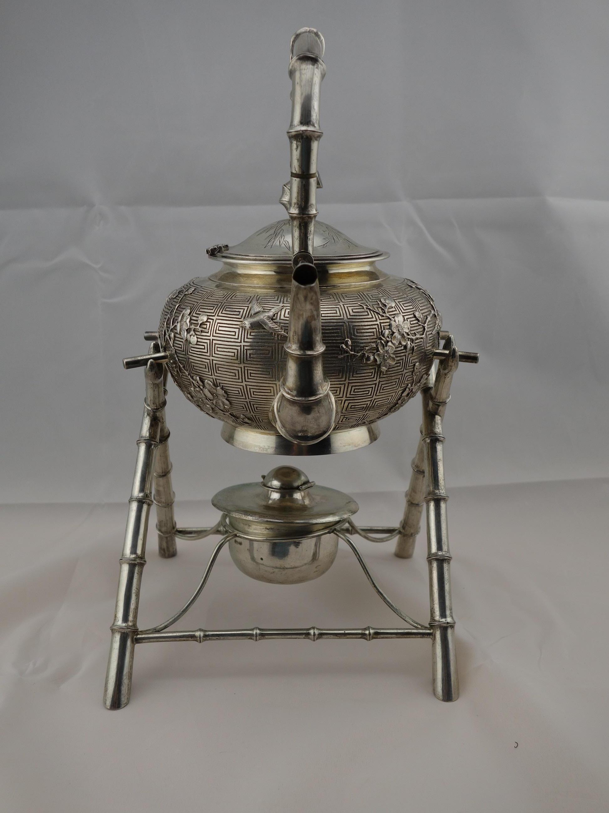 Chinese export silver teapot or kettle on a stylized bamboo stand decorated with birds by Hung Chong. The surface of the teapot has repousse background with cast, chased and applied bird and floral decoration. Preserved gold wash inside.
Hung Chong