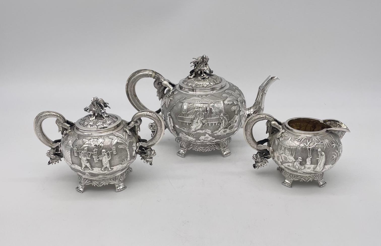 A Chinese Export Silver Teaset, of round form, with dragon handles and finials, and bamboo feet. This delightful three piece teaset is beautifully decorated with figural scenes and is a lovely example of the Chinese silversmith  良生 (Liangsheng) who