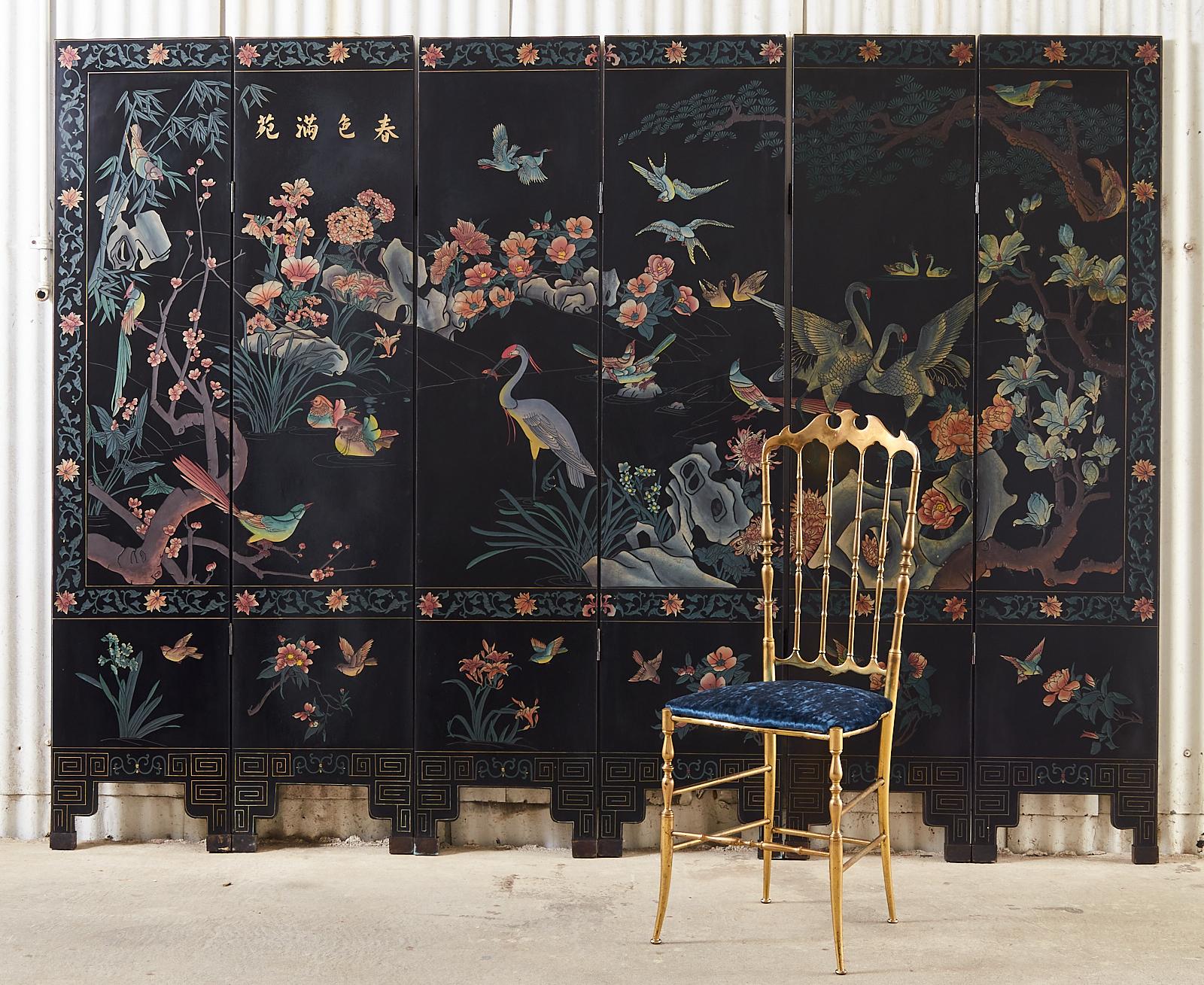 Colorful Chinese export lacquered six-panel coromandel screen depicting a busy flora and fauna landscape scene. Decorated with intricate flowers and exotic birds with a floral vine border. Each panel is lacquered, incised, and painted with natural