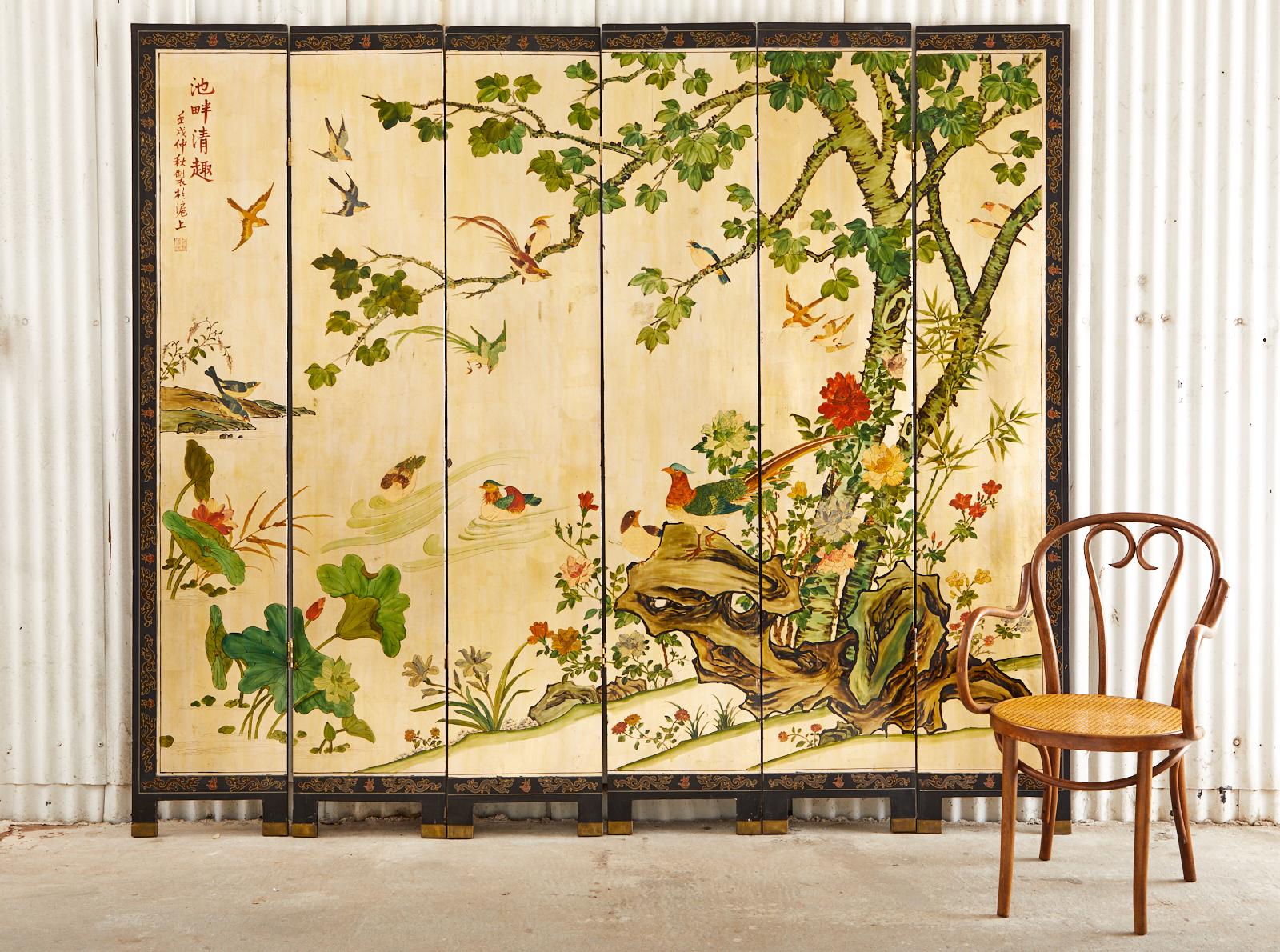 Radiant Chinese export six-panel coromandel screen. Featuring lacquered panels over a dramatic gilt gold leaf square ground. Beautifully hand-painted with intricate details depicting a flora and fauna landscape scene at a river's edge. Delicate