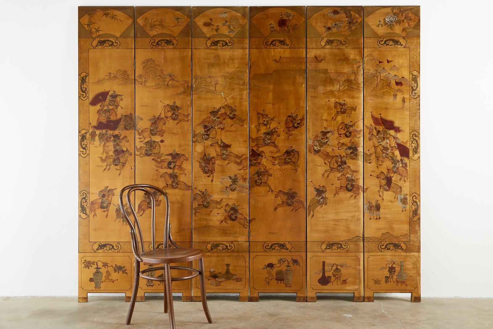 Fascinating Qing style Chinese export six-panel coromandel screen featuring a lacquer painted battle scene on a dramatic gilt background. The scene is bordered by a dragon motif and has decorative fans on the top of each panel and floral vases with