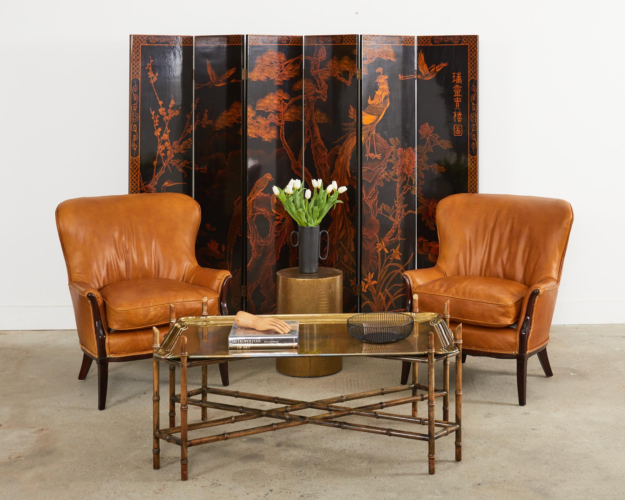 Dramatic Chinese export six-panel folding coromandel style floor screen featuring an idyllic landscape with exotic and mythical birds. The lacquered panels are intricately painted with an amber or burnt orange tone over a black ground with a gloss