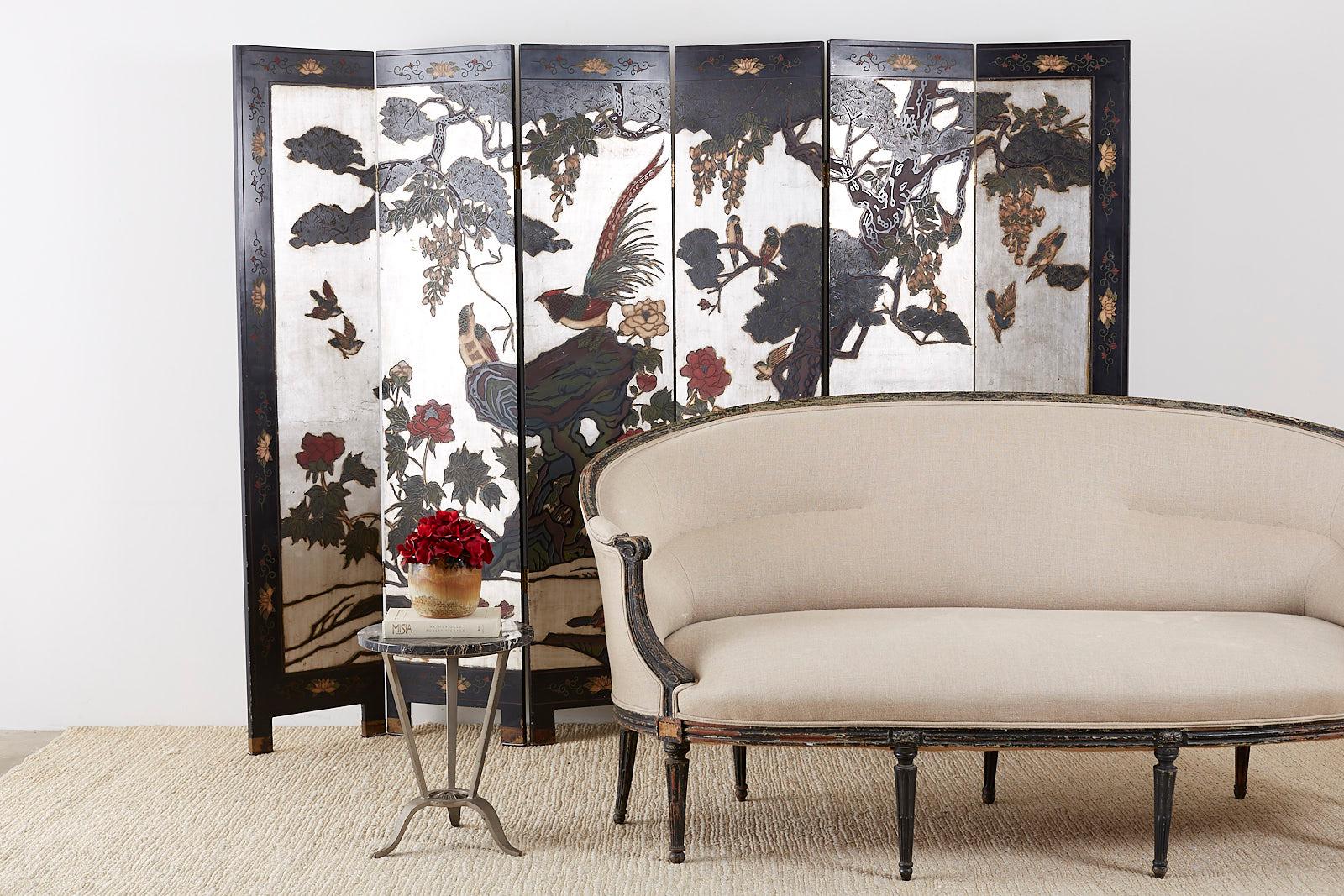 Impressive Chinese export six-panel folding coromandel screen depicting flora and fauna. Constructed from lacquered wooden panels hand carved and painted. Features a rare silver leaf background that make the scene Stand out with vibrant colors and
