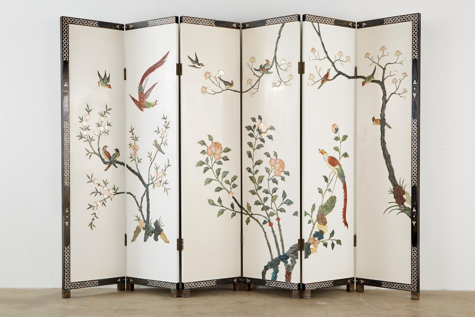 Captivating Chinese export coromandel style six panel screen featuring carved soapstone and hard stone. Exotic birds and flora over a dramatic white lacquered field. The intricately carved stones stand out boldly with precious gemstone shades over