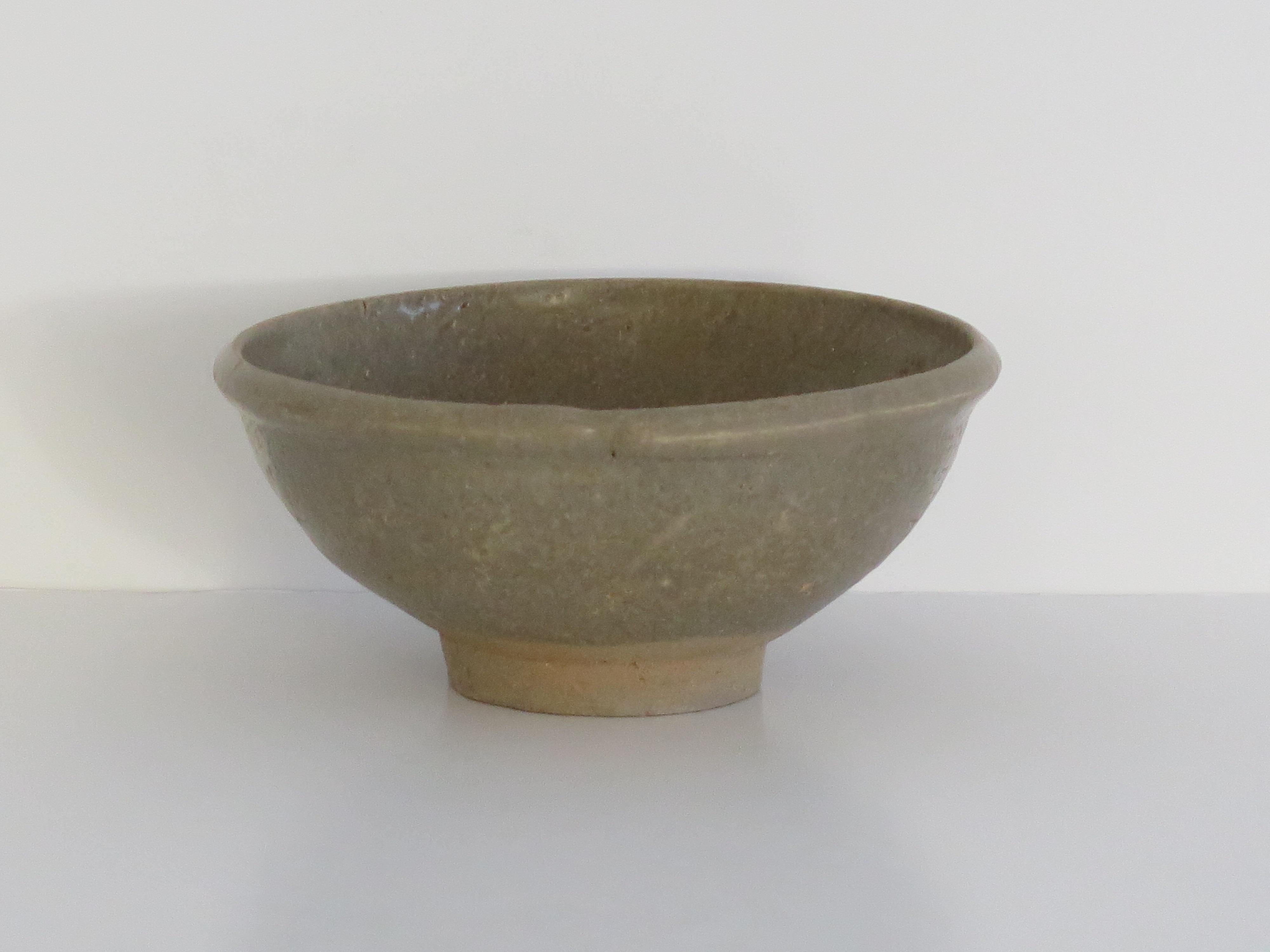 This is a very old interesting Chinese Export stoneware Longquan Celadon bowl, which we date to the early Ming or later Yuan Dynasty, circa 1400 or earlier.

The bowl is well potted with a fairly thick rim and on a high foot. The glaze thickness
