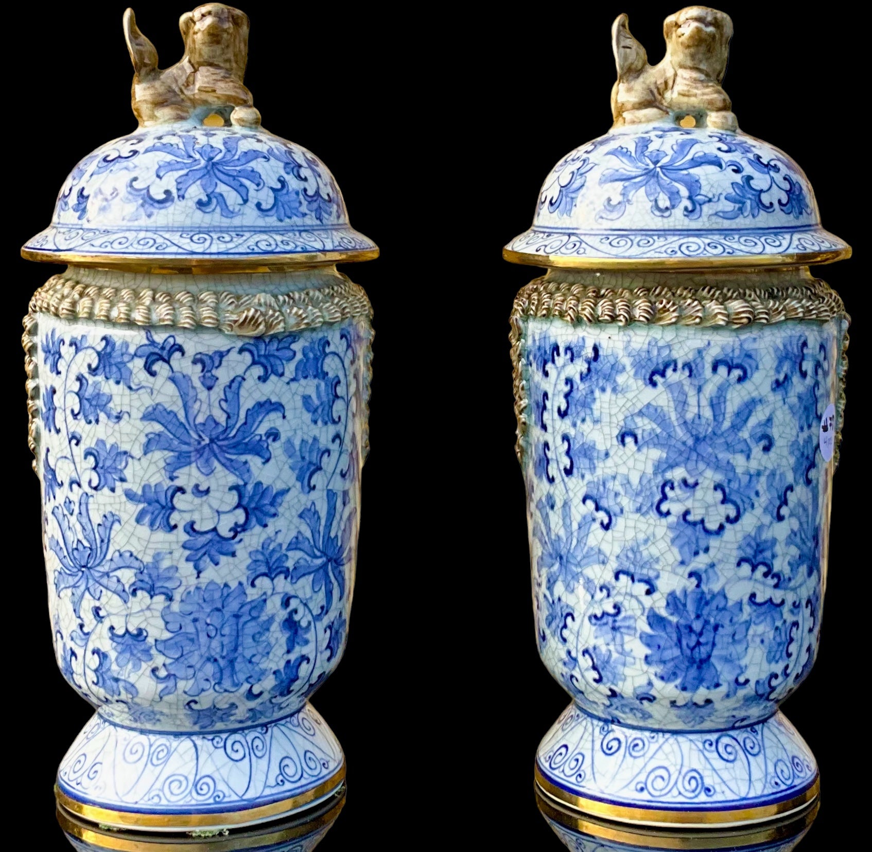 Voici une paire de jolis pots à gingembre en céramique bleue et blanche de style export chinois. Ils ont des accents dorés et des embouts en chien de faïence. La poterie est intentionnellement craquelée. Ils sont marqués.