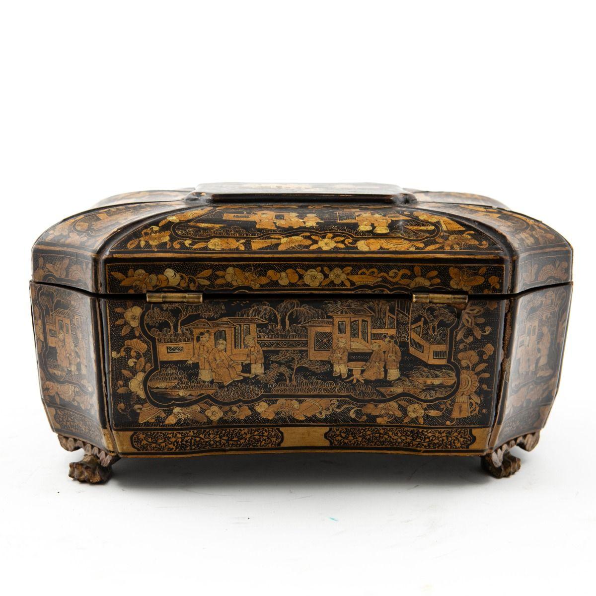 Eine wunderschön gearbeitete chinesische Export-Teekanne aus Holz mit schwarzem Lack, reich verziert mit vergoldeten Motiven, die klassische chinesische Szenen von Menschen, Häusern und mehr zeigen.
Das Kästchen ruht auf kunstvoll geschnitzten und
