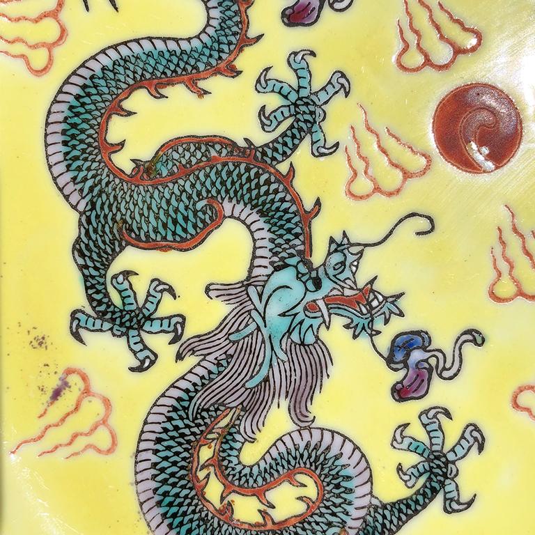 Famille jaune Yellow enameled chinoiserie plate or platter. Piece features two 5 claw scaly sancai Dragons on a pale yellow background. The perimeter of the plate is decorated with a greek key pattern in blue, red and yellow, on a mint green