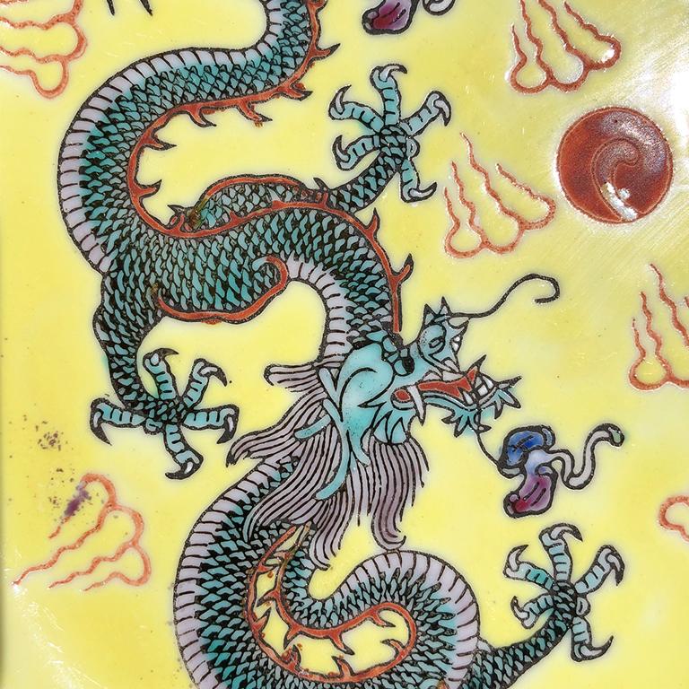 Famille jaune Assiette ou plateau de chinoiserie en émail jaune. La pièce présente deux dragons sancai à 5 griffes sur un fond jaune pâle. Le périmètre de l'assiette est décoré d'un motif de clé grecque en bleu, rouge et jaune, sur un fond vert