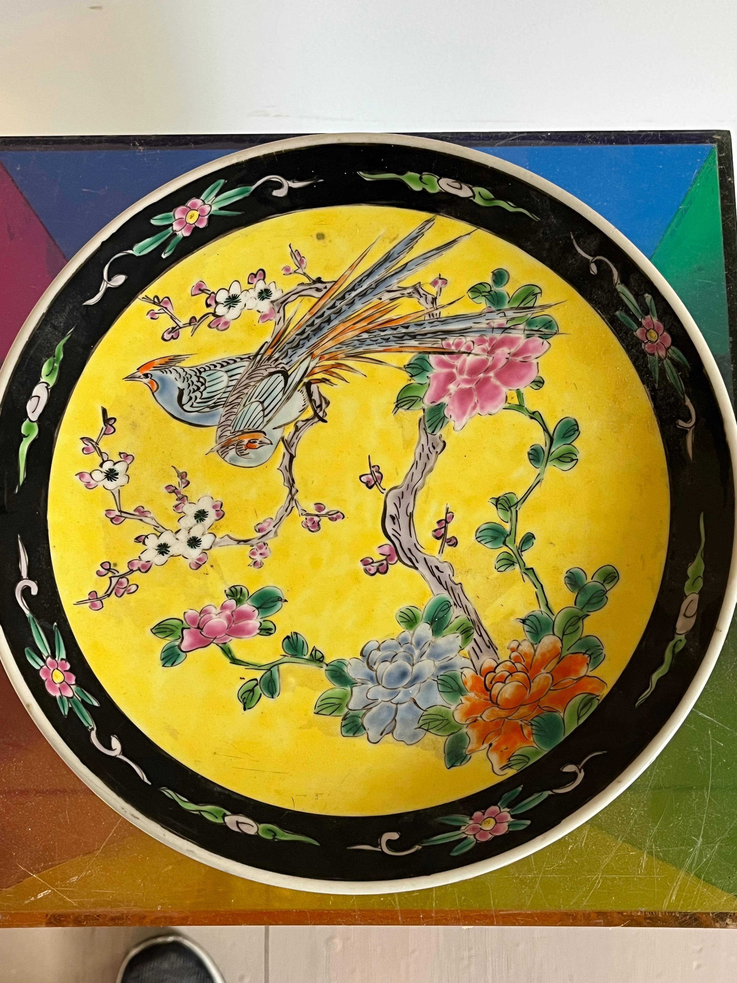 A hand-painted Chinese decorative display plate in the Famille Jaune manner, from the Qing period circa 1900, depicting a pair of birds in a cherry blossom tree. 
