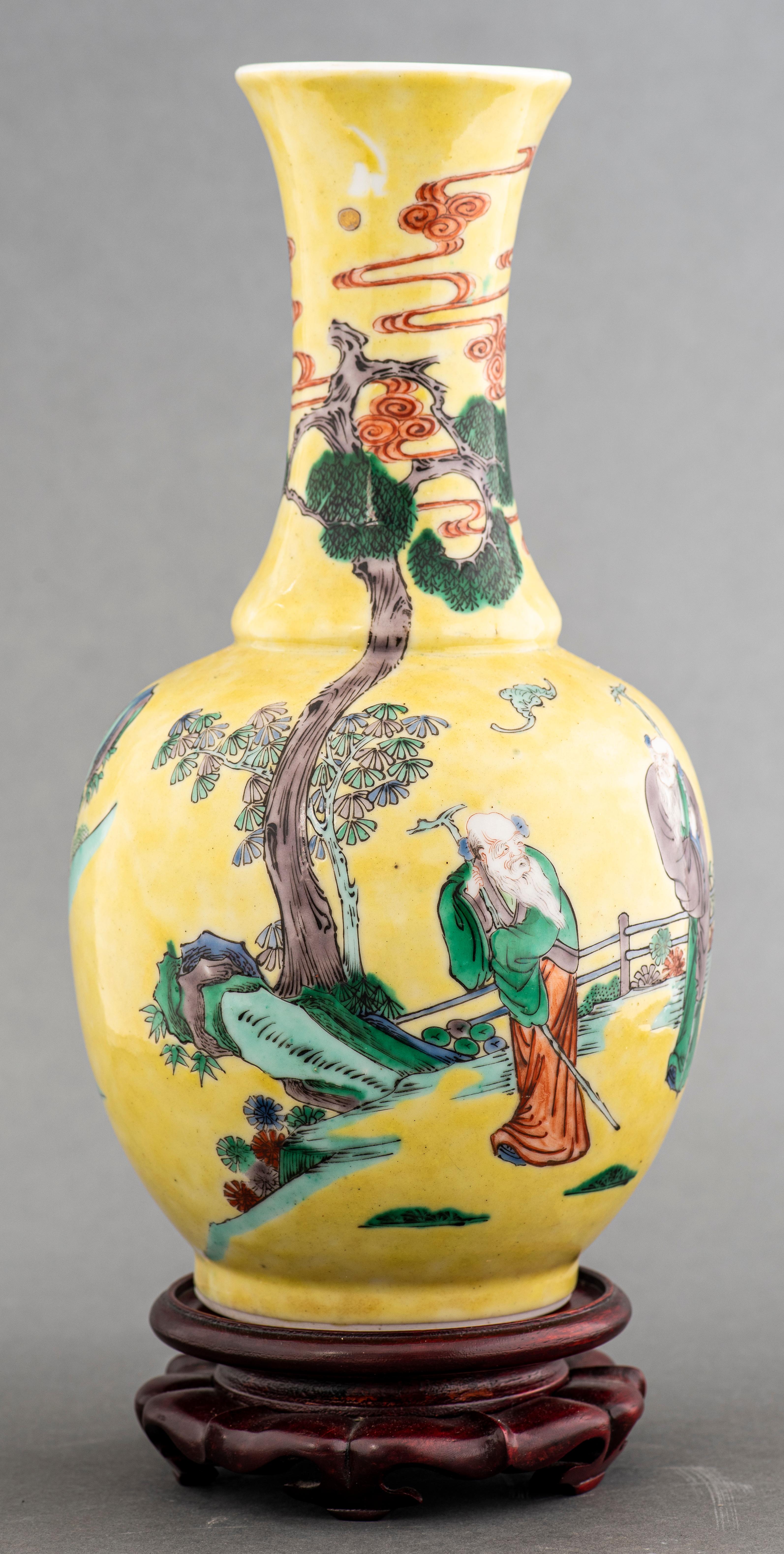 Chinese Famille Jaune baluster form vase with yellow ground, decorated with deities or other figures under auspicious motifs, including scrolling clouds and flying bats, mid 20th century, raised on wood stand. 
Dimensions: Vase: 11.25