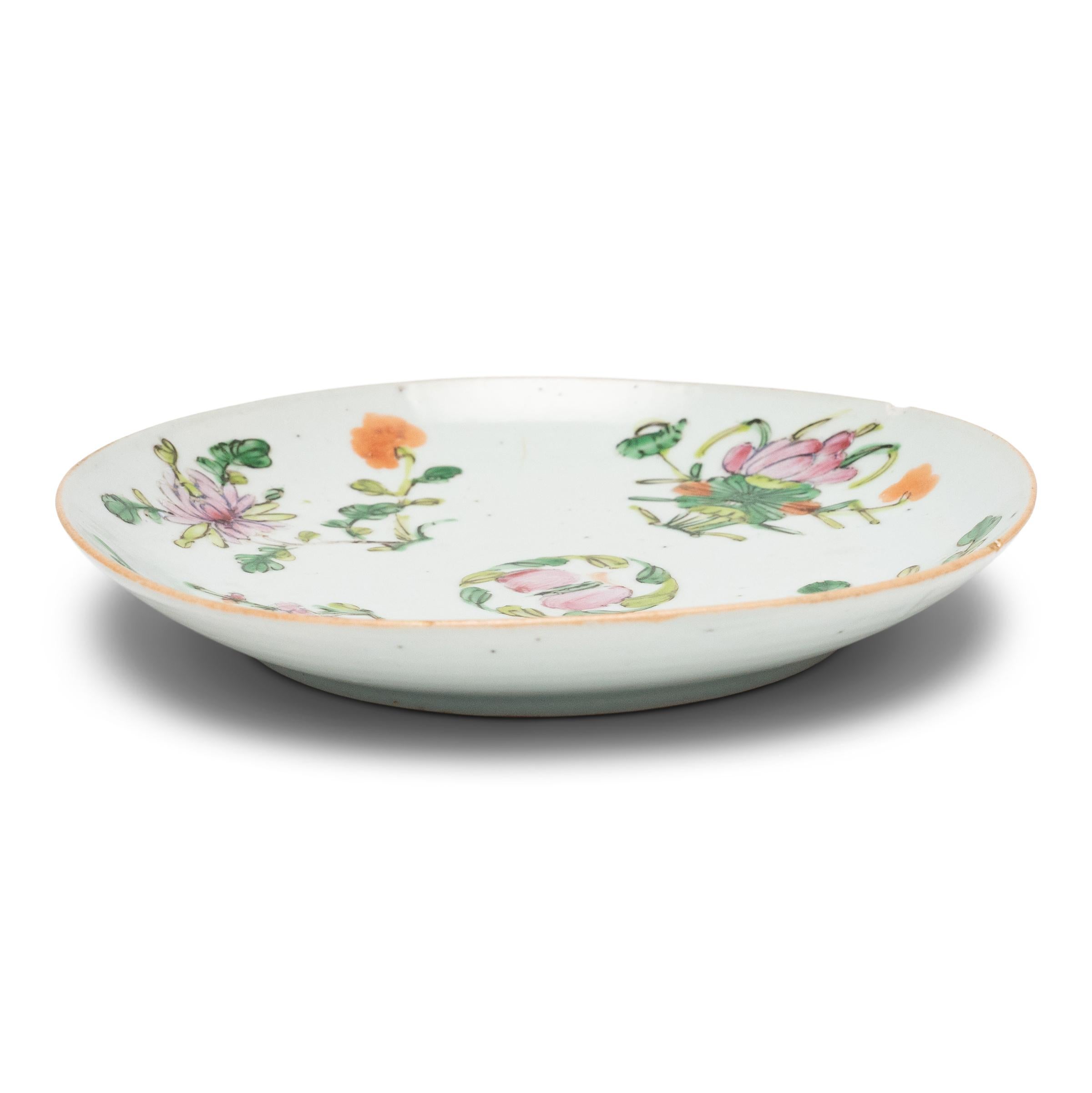 Painted with overglaze enamels in the famille rose style, this small porcelain dish has a colorful design of four flowers representing the seasons. Rendered in shades of pink, green and orange, the motif includes a spider chrysanthemum for autumn,