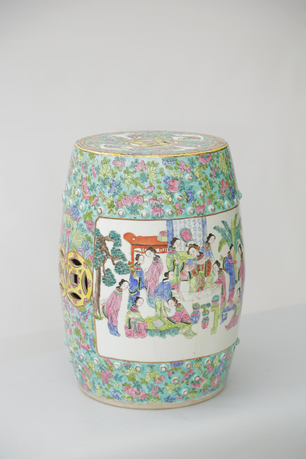 Famille Rose garden seat, of handpainted porcelain, its traditional studded drum shape is intricately decorated in a pastel palette of blues, greens, yellows, and pinks, its body decorated with a figural scene of court life, opposite a pair of