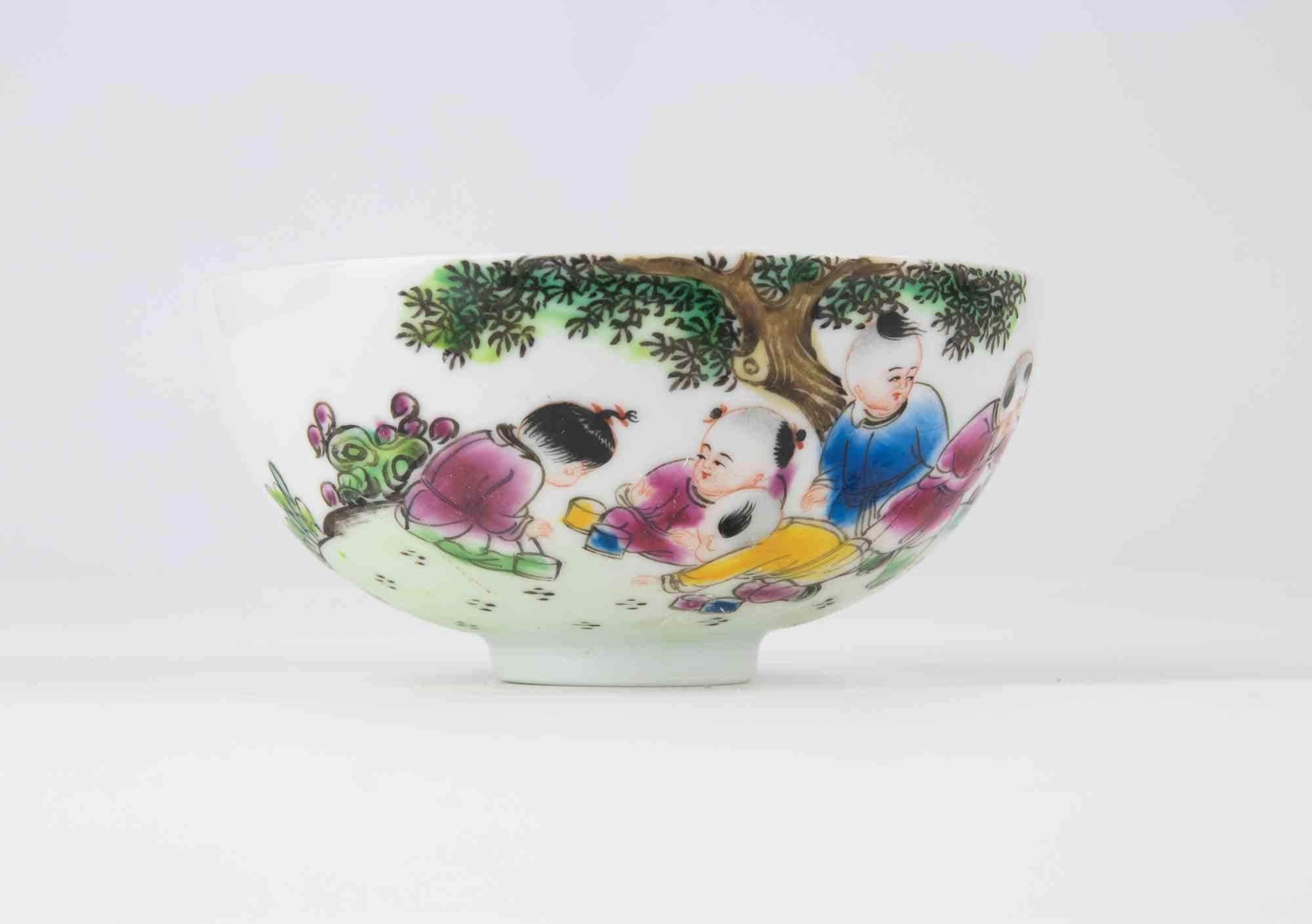 Bol en porcelaine finement empoté et délicatement peint à la main dans de vibrants émaux de la famille rose. L'extérieur est décoré d'une scène continue d'enfants enjoués sous un arbre feuillu, dans des tons vifs de rose, de bleu, de jaune et de