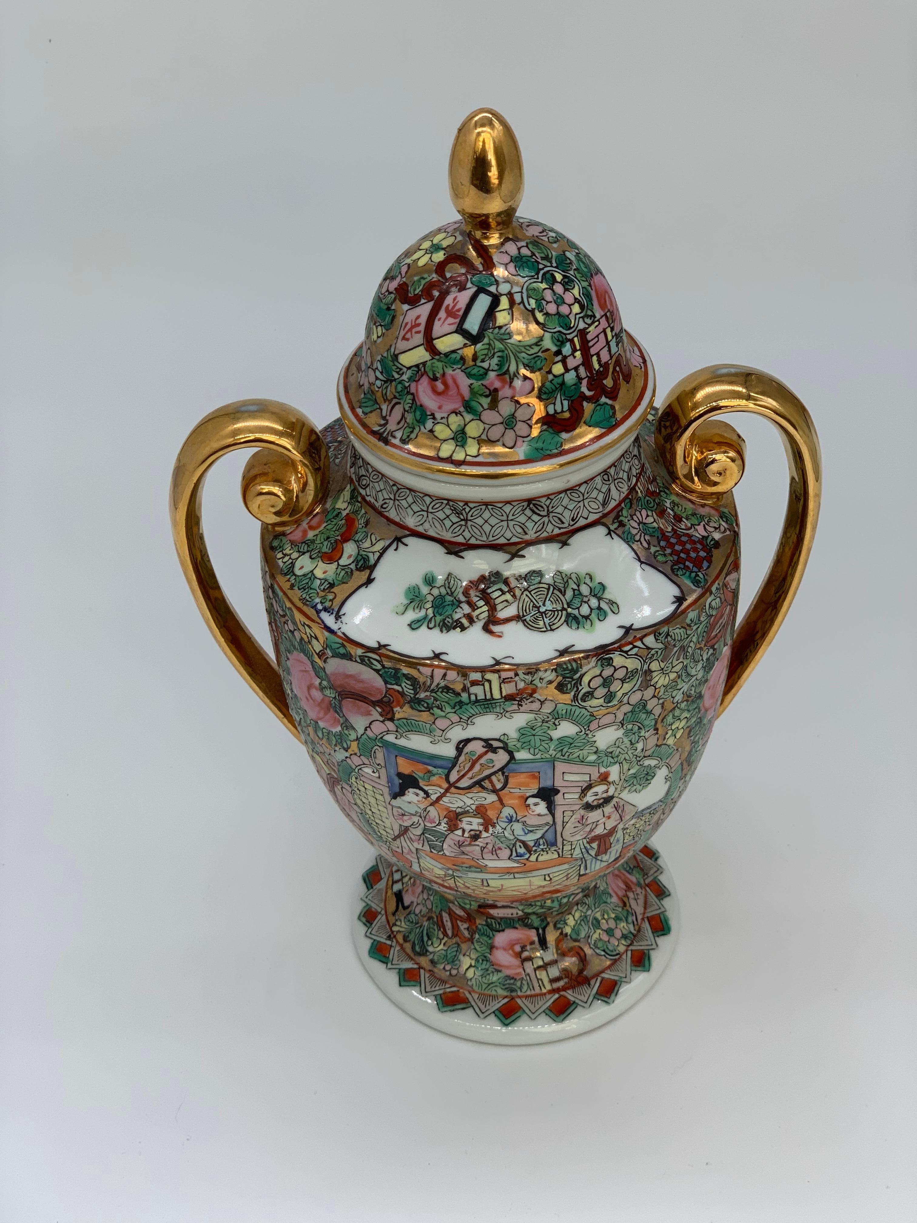 Ce magnifique vase de la famille rose avec des poignées dorées et des éléments dorés à l'intérieur du vase peint de façon complexe est rempli de motifs figuratifs et floraux.
Le vase présente des scènes de cour et des vignettes florales dans une