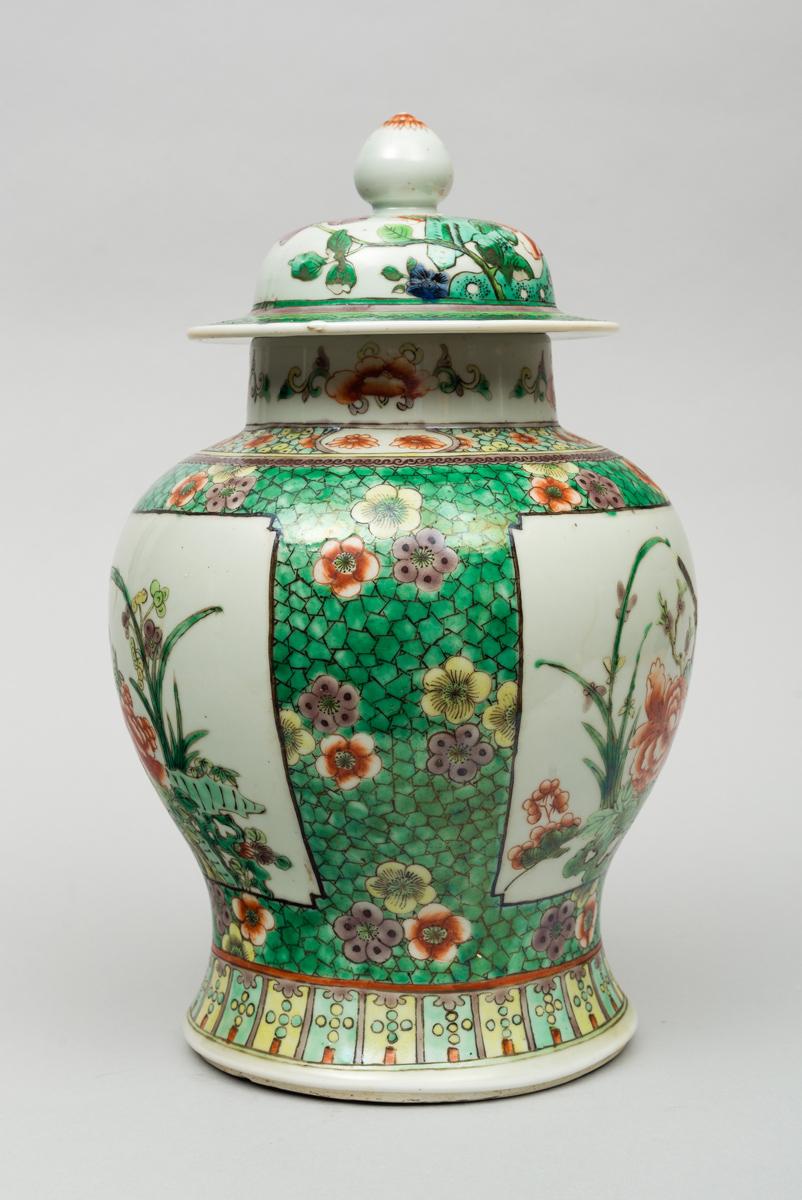 Chinese porcelain famille verte baluster-shaped vase and lid decorated with two large panels enclosing birds perched on flowering tree branches, the panels are on a green cracked ice background with stylized flower heads. The lid is decorated with