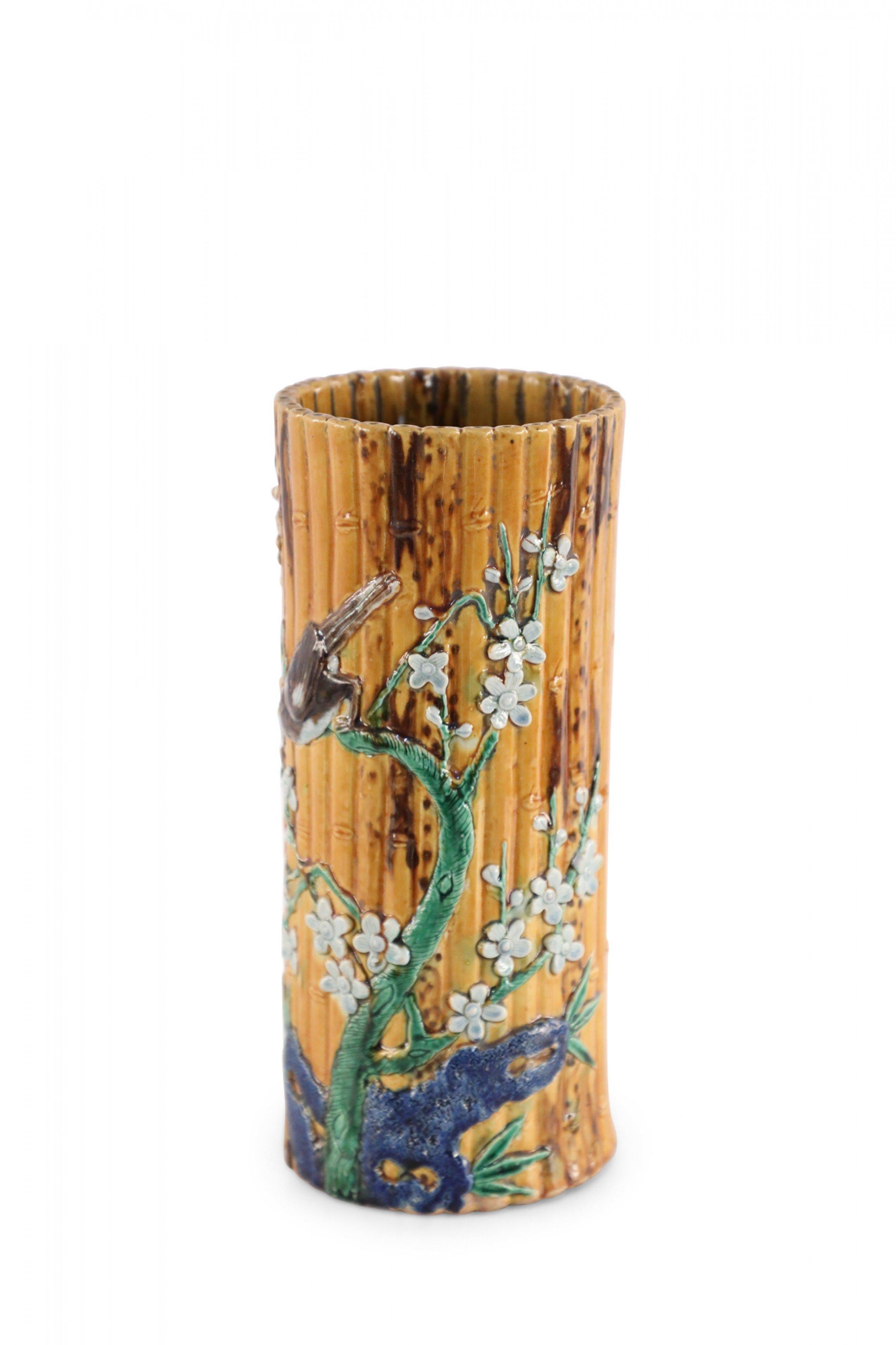 Zylindrische Porzellanvase aus chinesischem Bambusimitat in einer Form, die im alten China traditionell als Hutständer verwendet wurde, verziert mit dem erhabenen Motiv eines Vogels, der auf einem blühenden Zweig sitzt.
      