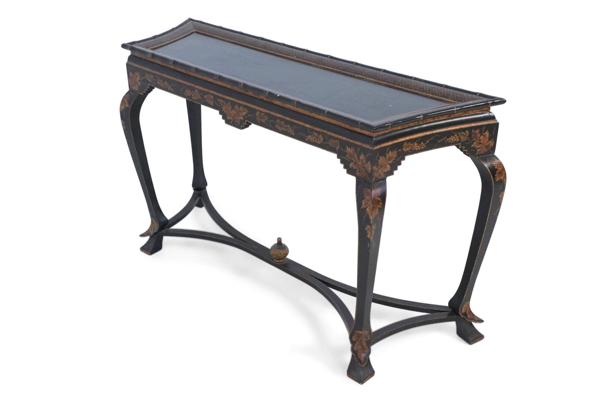Chinese black painted console table topped with faux bamboo trim, a trapezoidal shaped top framed in a gold lattice pattern, over an apron decorated in gold grape leaves, supported by cabriole legs connected with a stretcher that intersects at a