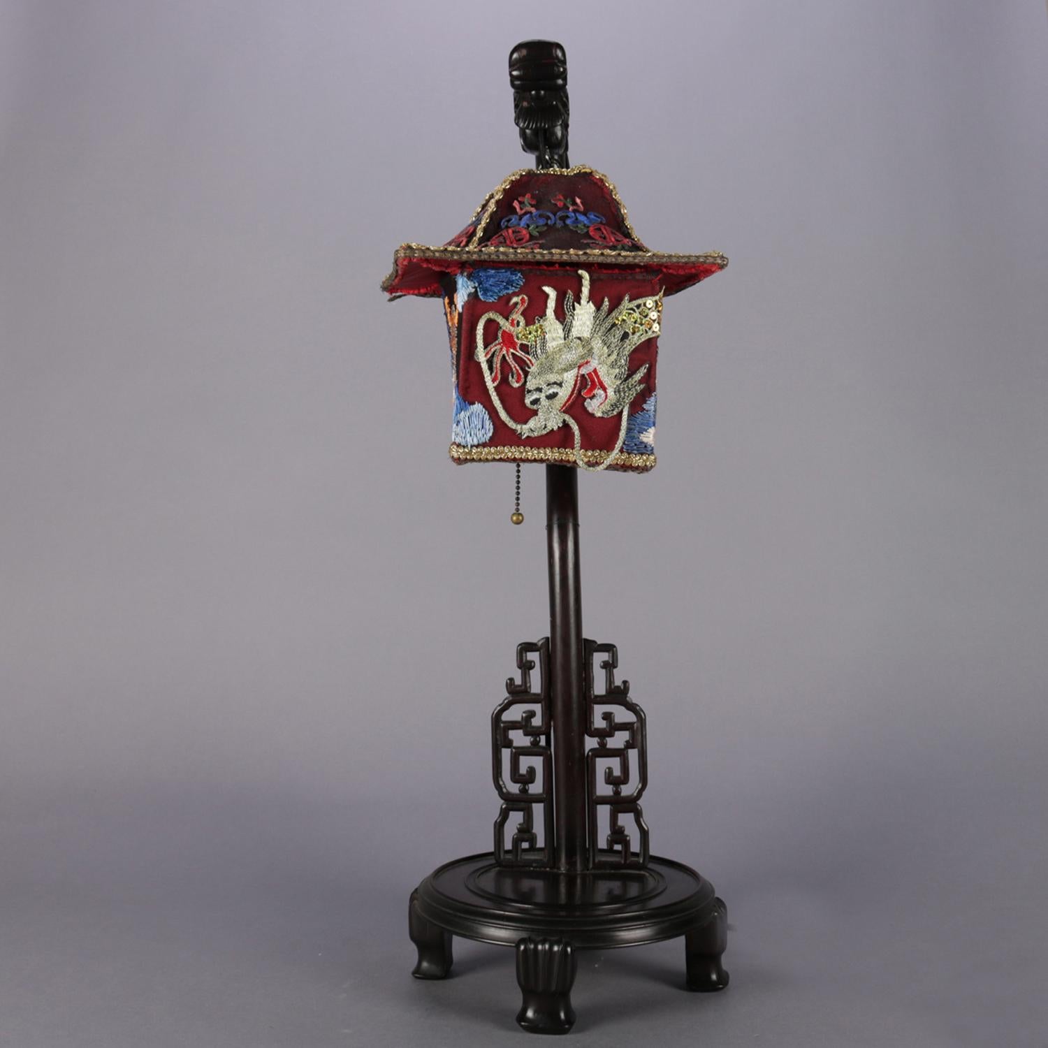 Chinese figural desk lamp features carved hardwood base in dragon form with pagoda form hanging shade heavily embroidered with dragon and gold decoration, working condition, 20th century.

Measures - 28