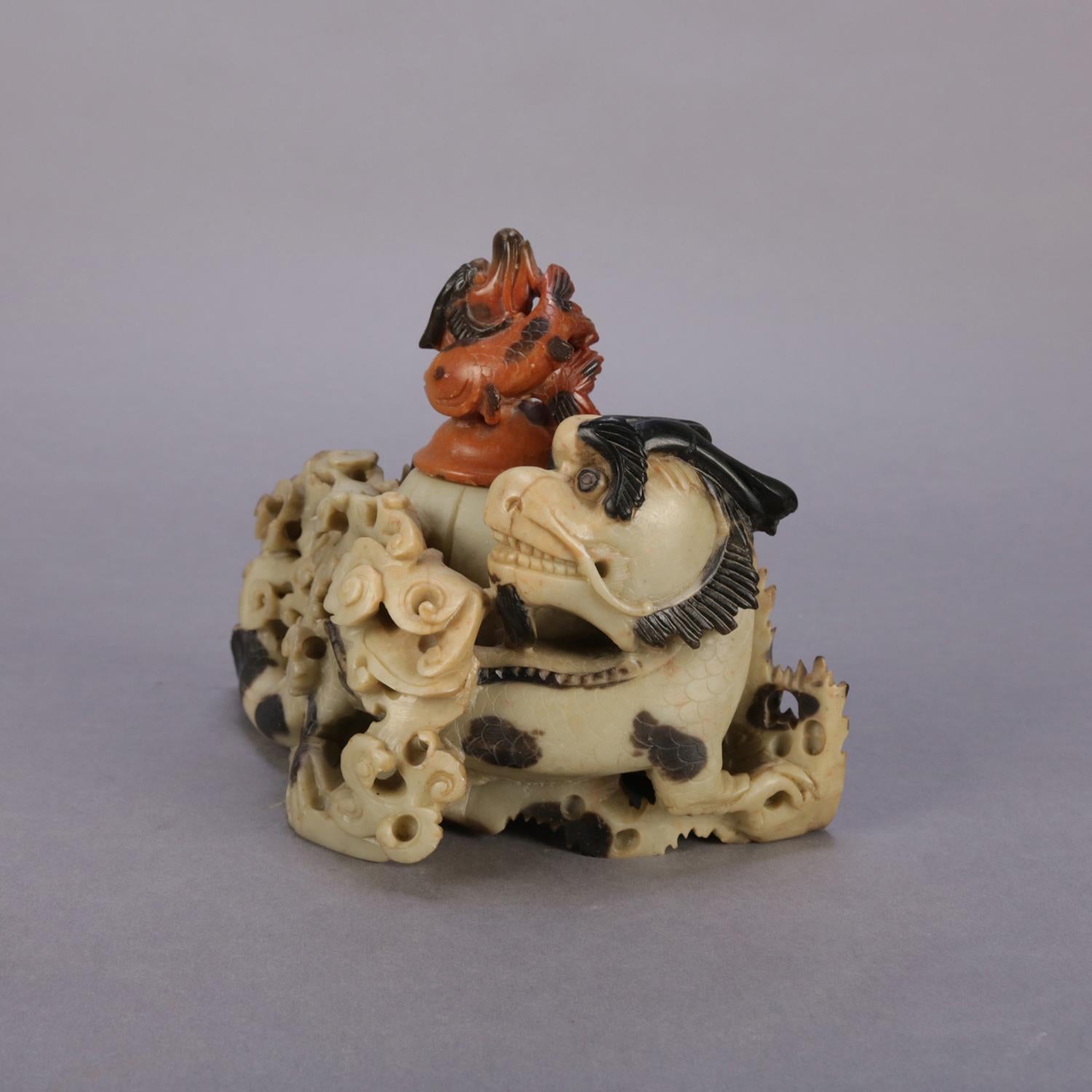 Antique figural Chinese carved soapstone sculptural inkwell features bi-colored dragon set in rolling sea waves and having carved top with koi (fish) finial, en verso dated with carved, 1900.

Measures: 5.75