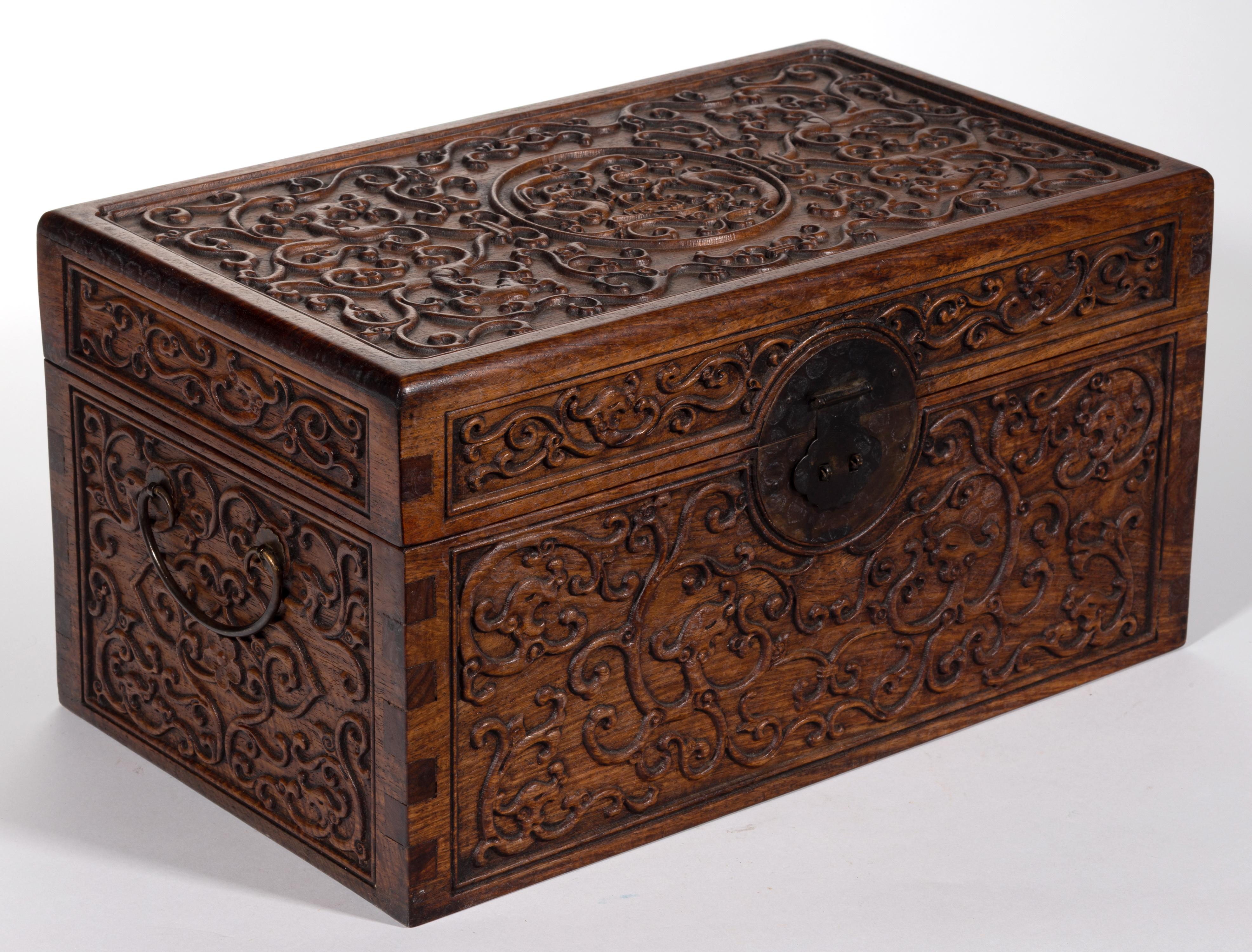 A Chinese rosewood Huanghuali document box with brass hardware including handles and lock latch. The surface of the box is finely carved in low relief of scrolling clouds and dragons. On the top surface, a roundel of double dragon design was placed