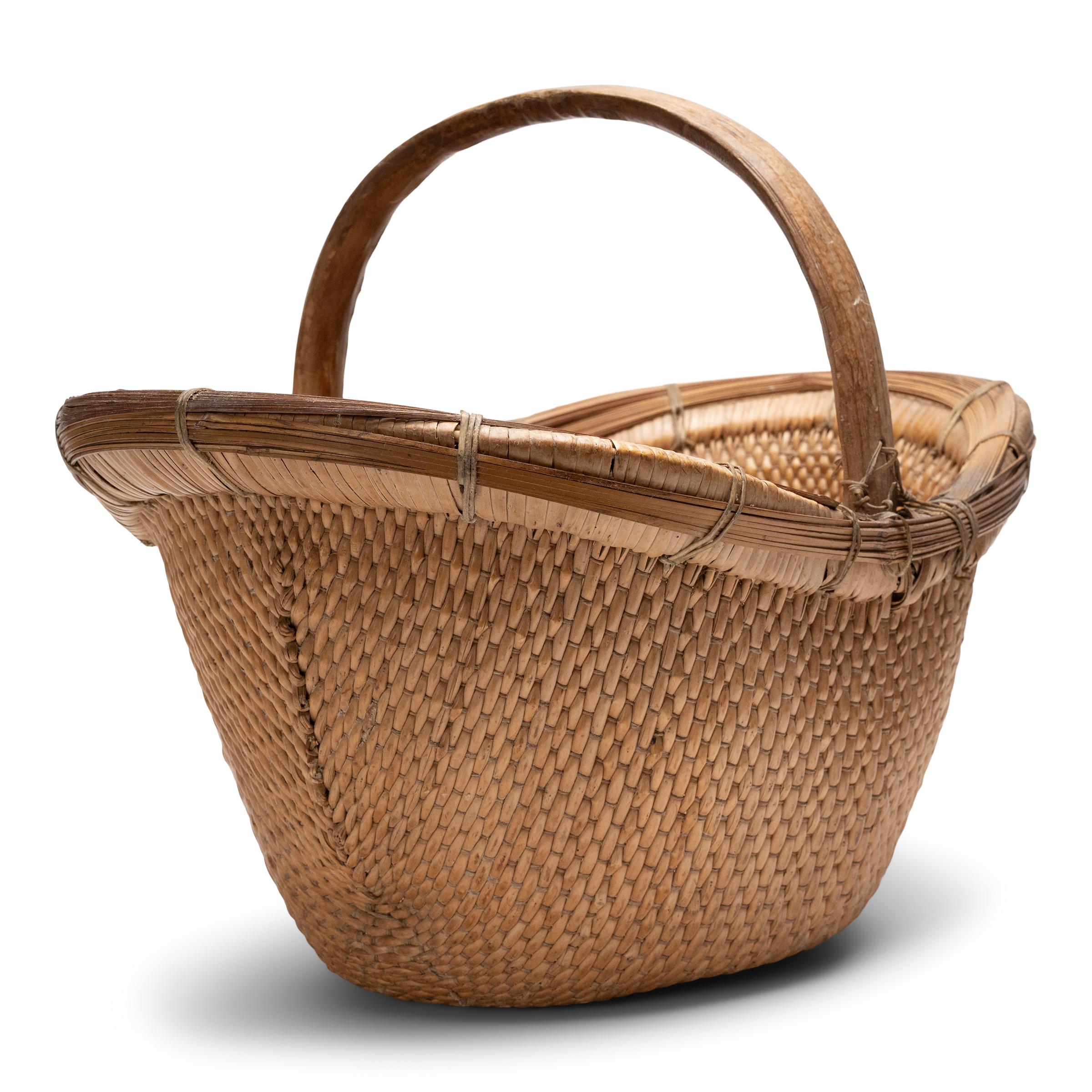 It is easy to imagine someone, long ago, gathering a harvest from their garden or strolling to the market with this beautiful basket tucked under their arm. Hand-woven of young willow branches and twine, the basket has deep, oblong body with a