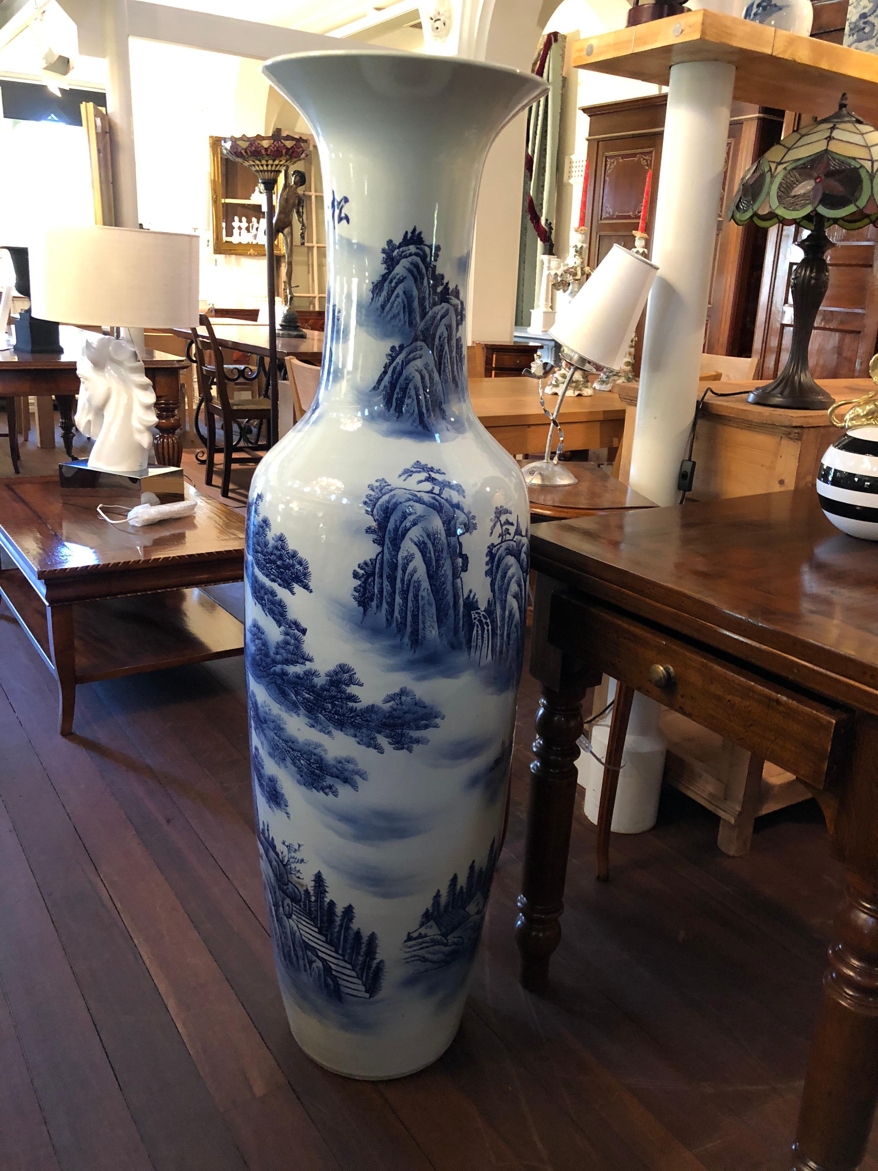 This fine depiction of a grand, traditional Chinese floor vase, features exquisite painterly blue and white mountainous, tree scenes and is structurally sound. Towards the top of the vase, there is Chinese symbols and delicate painted clouds. A