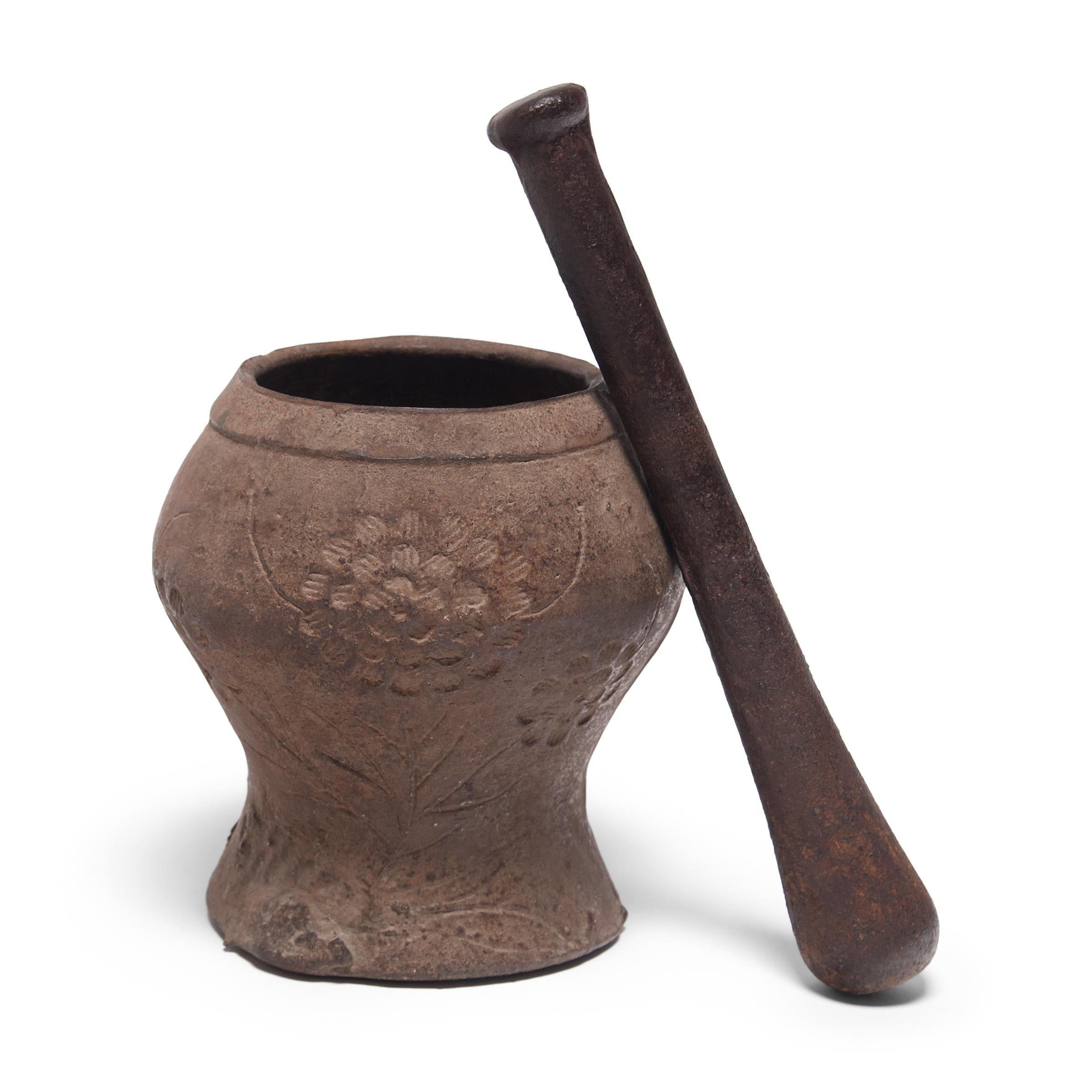 This vintage mortar and pestle from Shanxi, China was cast in iron with a floral relief. It was originally used in a traditional apothecary to create herbal medicine.